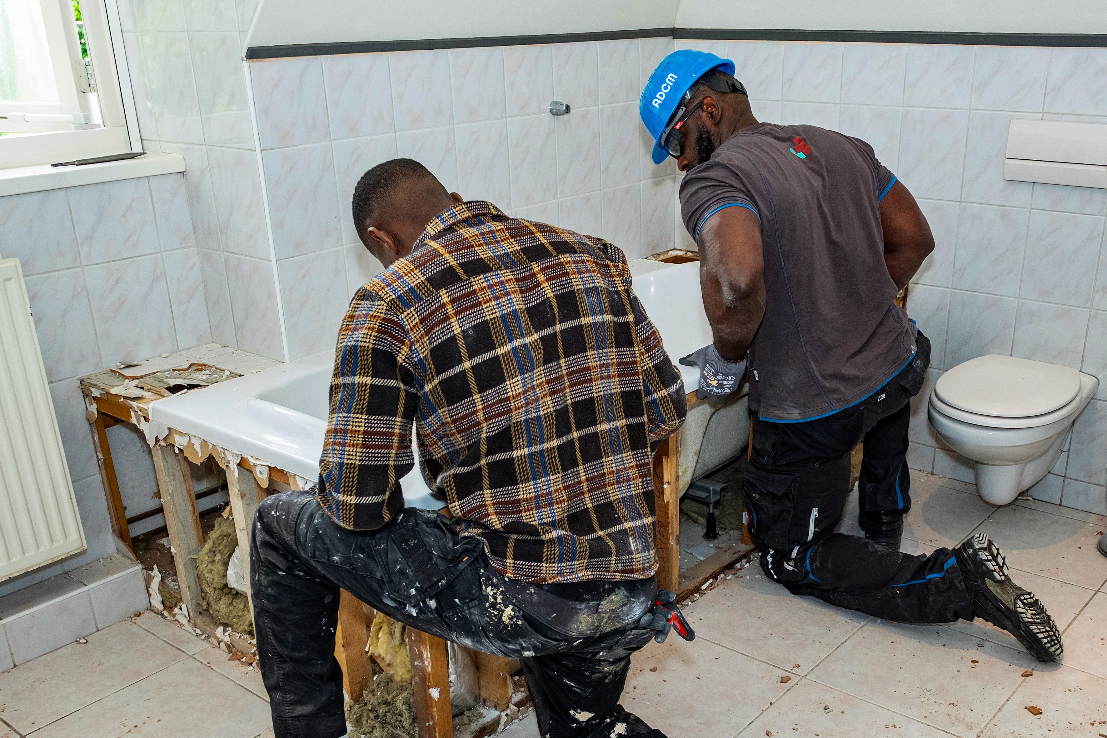 Badkamerrenovatie in uitvoering met twee vakmensen bezig aan het verwijderen van oud sanitair.