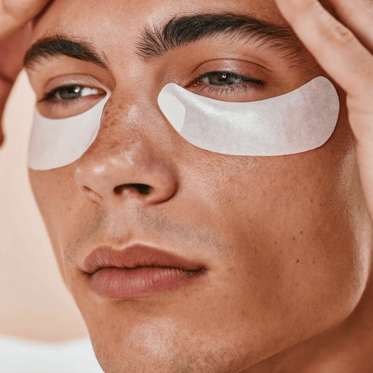 A man relaxes with under-eye patches, eyes closed, focusing on his skincare routine.
