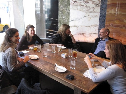 A photo of a group of people sitting at a restaurant table with glasses and coffee cups on it.