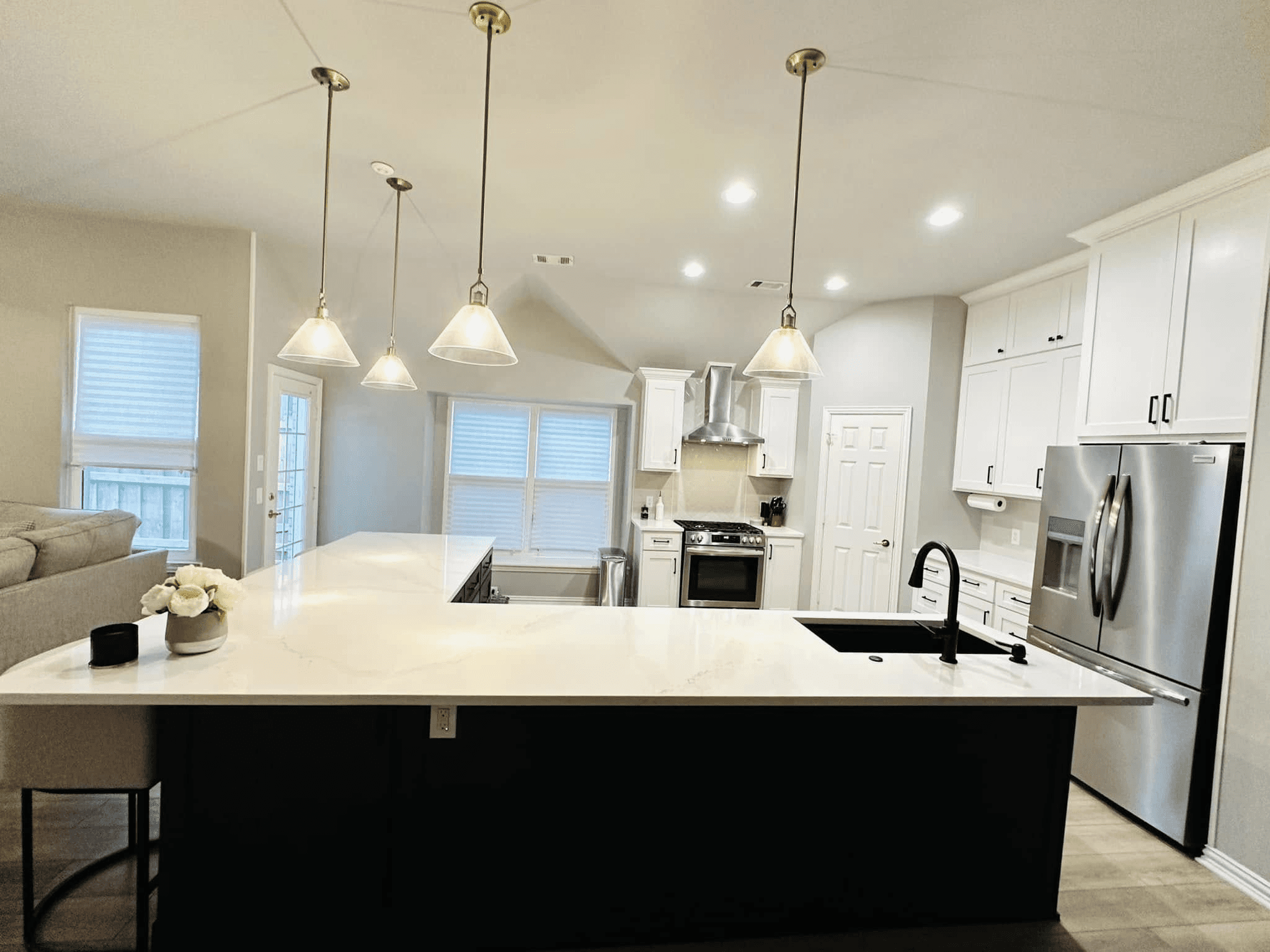 Connected kitchen design completed in Deep Ellum, Texas featuring an open-concept layout, large island, modern lighting, and improved flow between the kitchen and living areas.