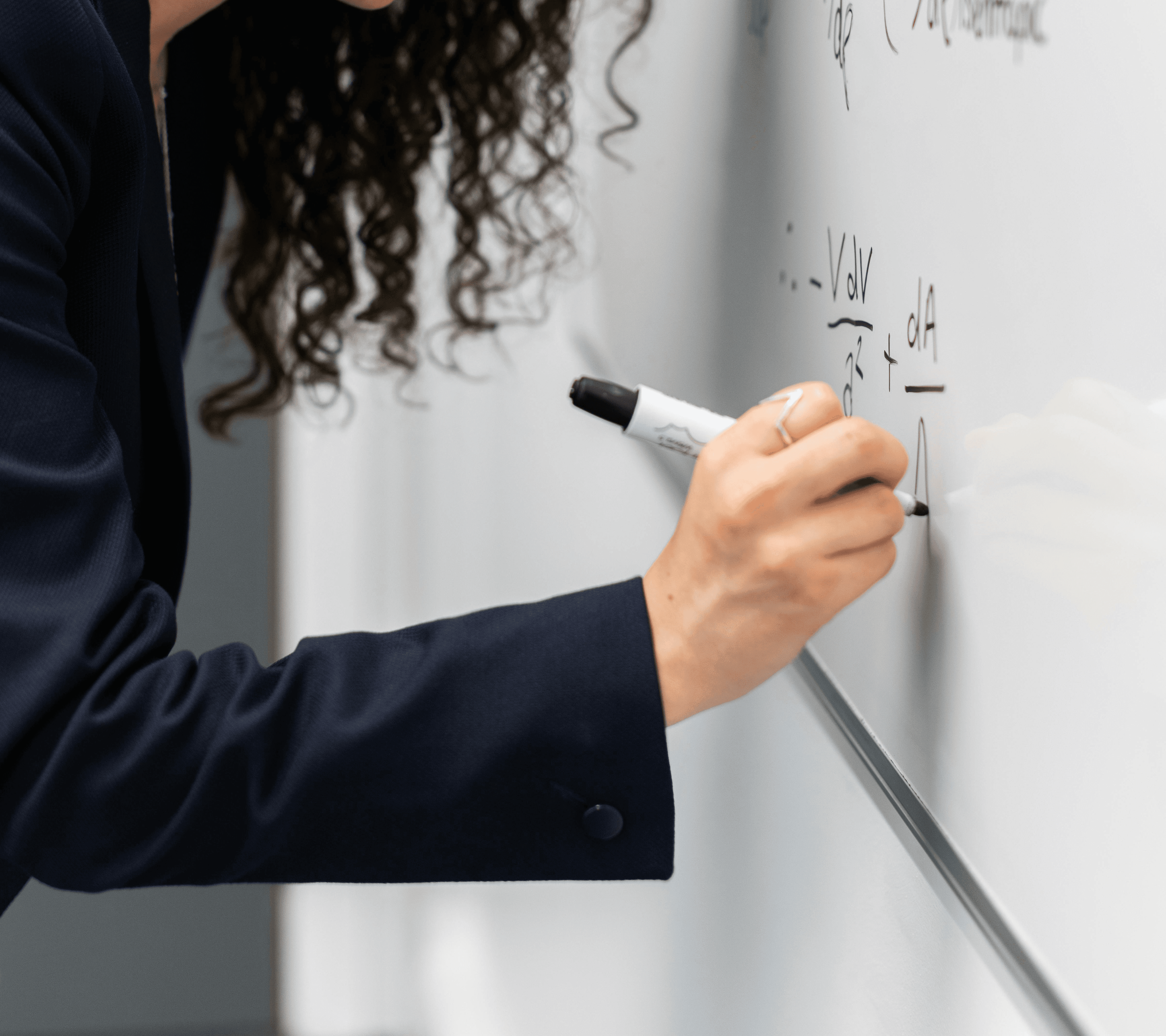 A winding road cuts through rocky terrain, surrounded by patches of green grass and illuminated by sunlight.