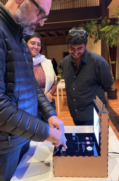A visitor presses Mix A Pixel’s buttons while two others watch and smile