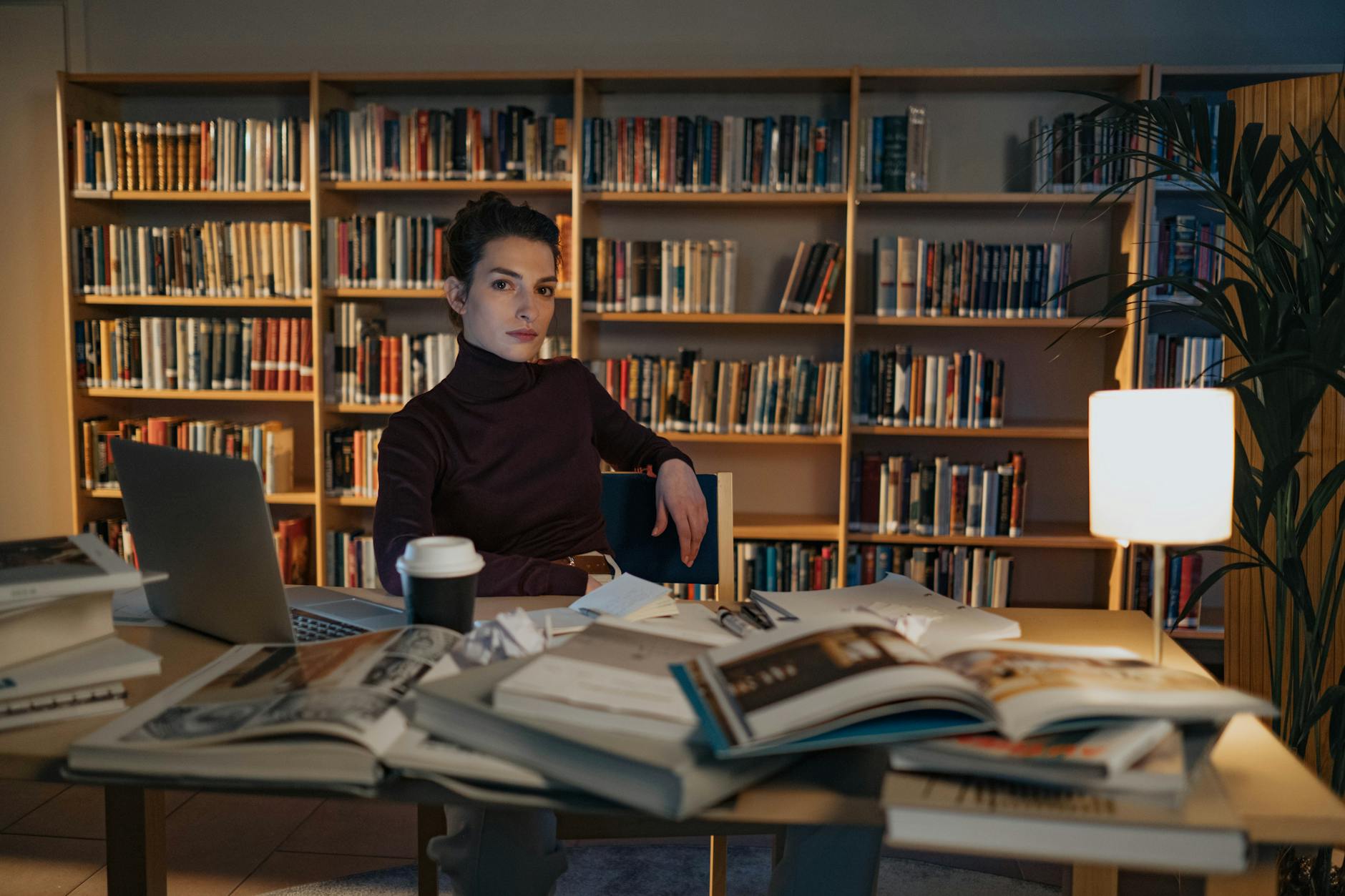 A high school student working quietly at their desk, writing in a notebook with a focused expression.