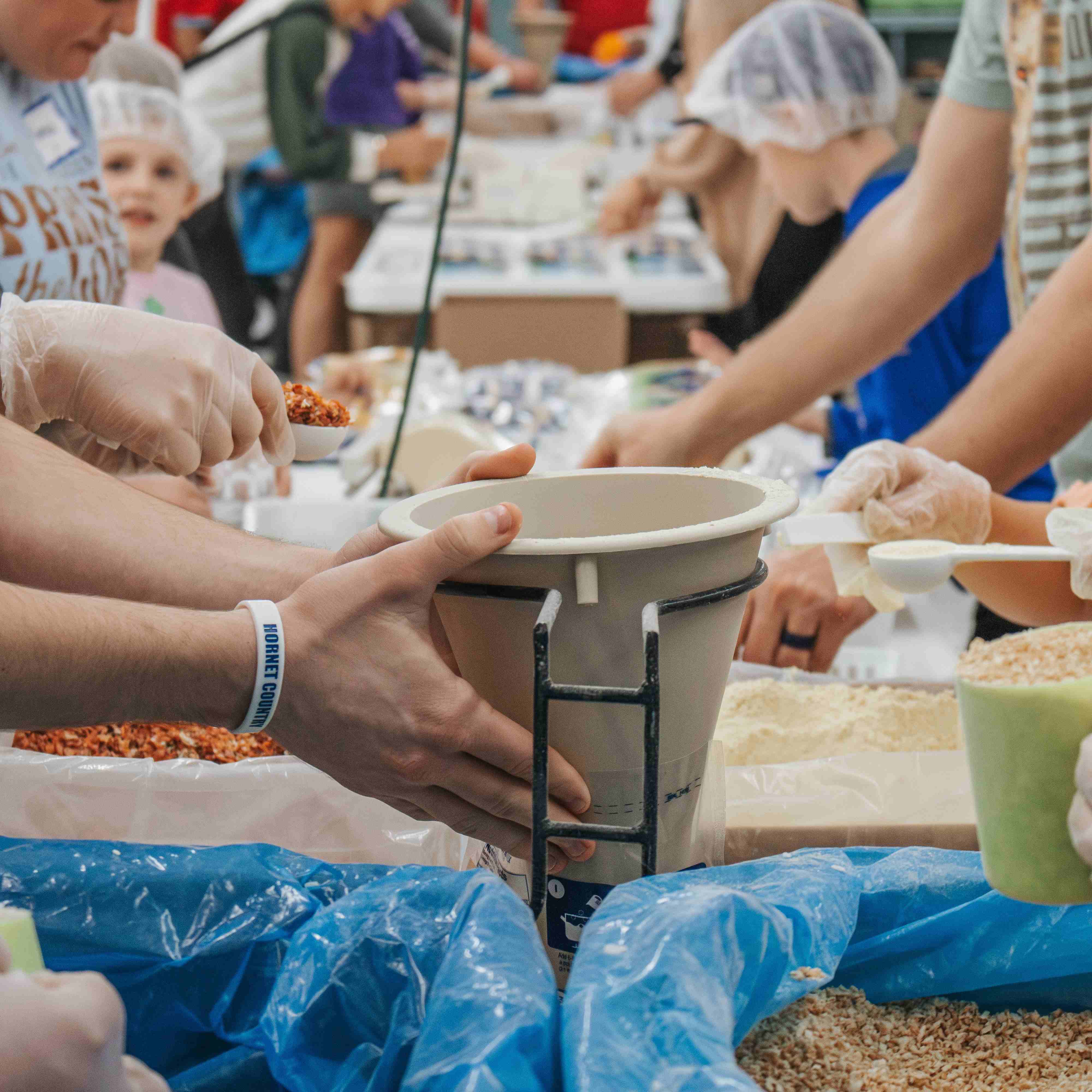 Hands are filling up rice bags to send overseas at teh Hope Factory at A Child's Hope Int'l.