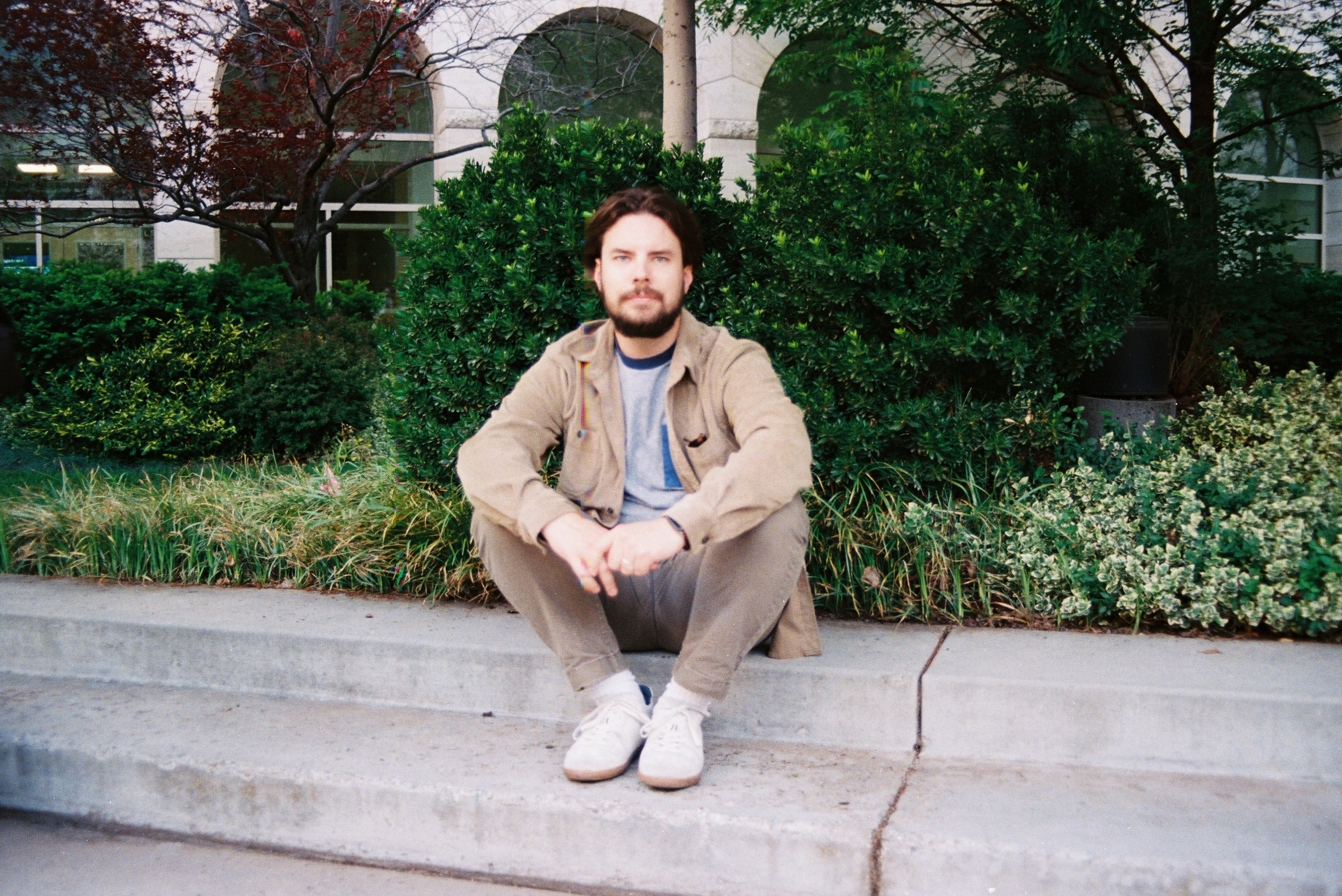 Photo of Brendan sitting on steps with folliage in the background