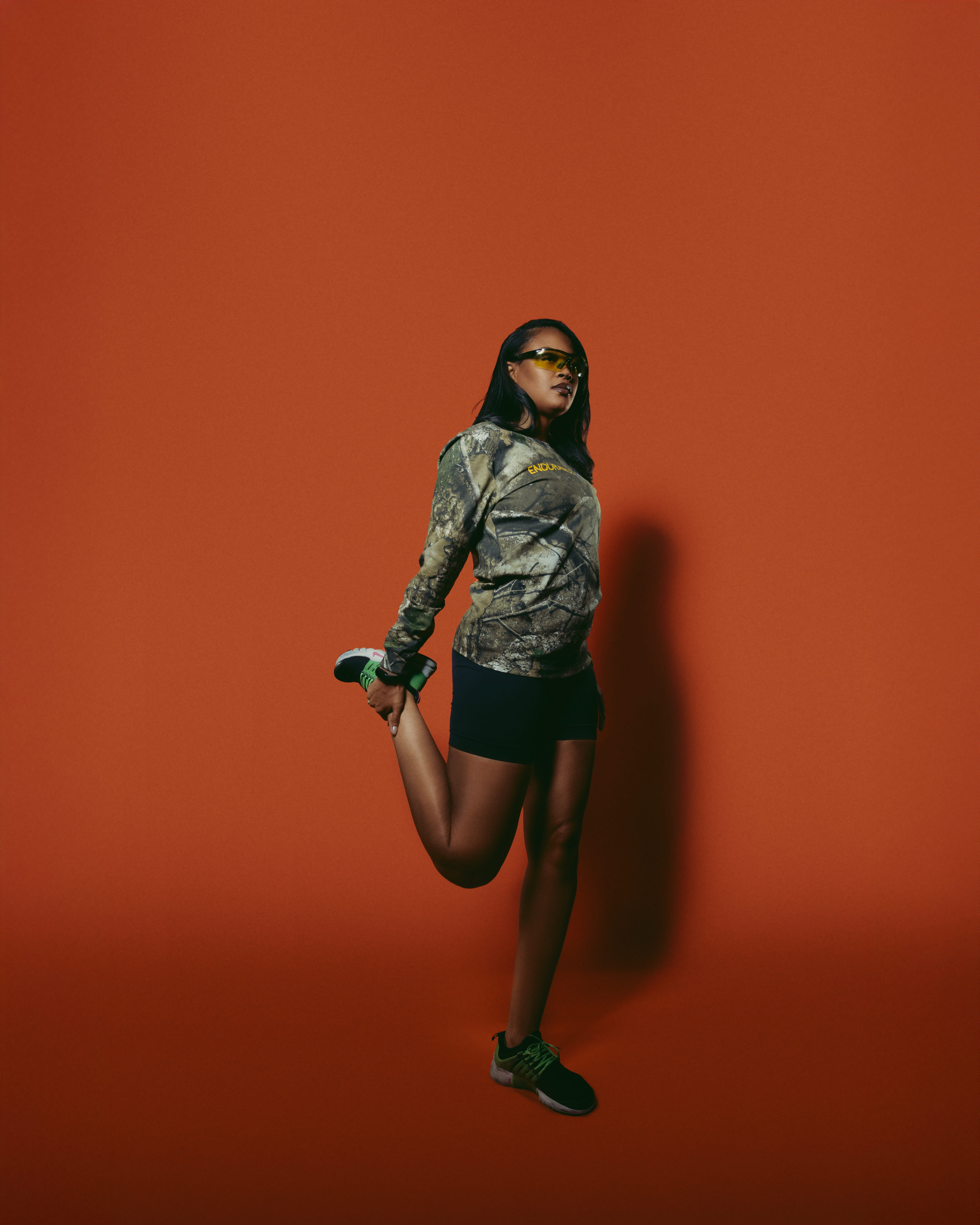 endurance run club runner stretching one leg in studio against a red background