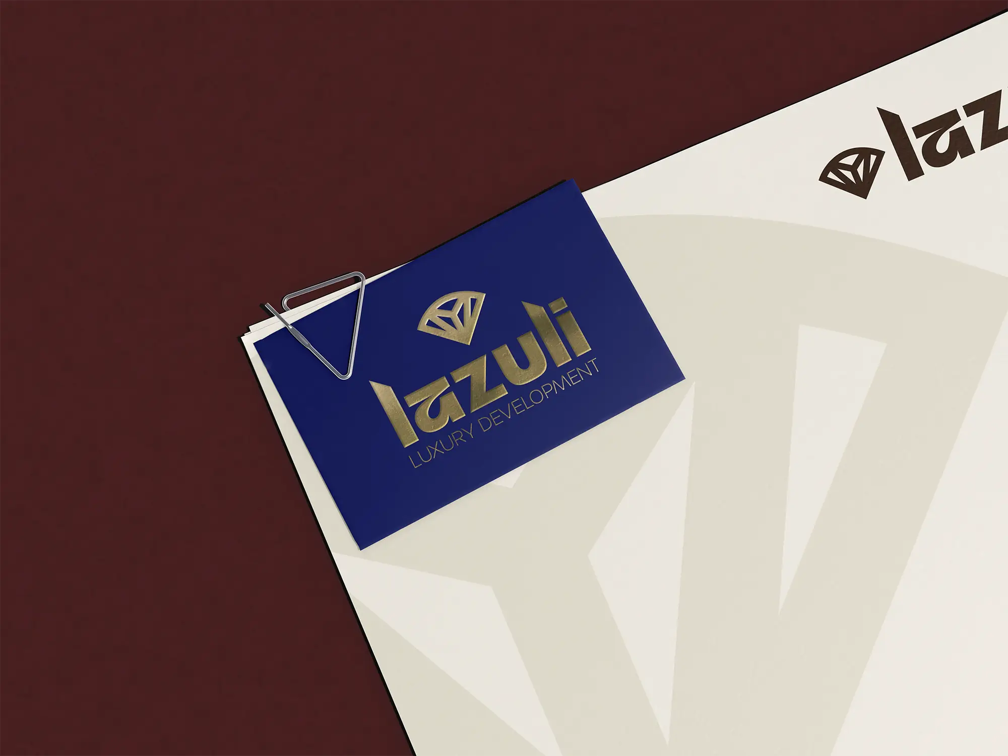 Navy Lazuli Luxury Development business card clipped to a cream letterhead on a maroon background