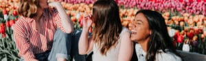 three girls laughing in a field of flowers