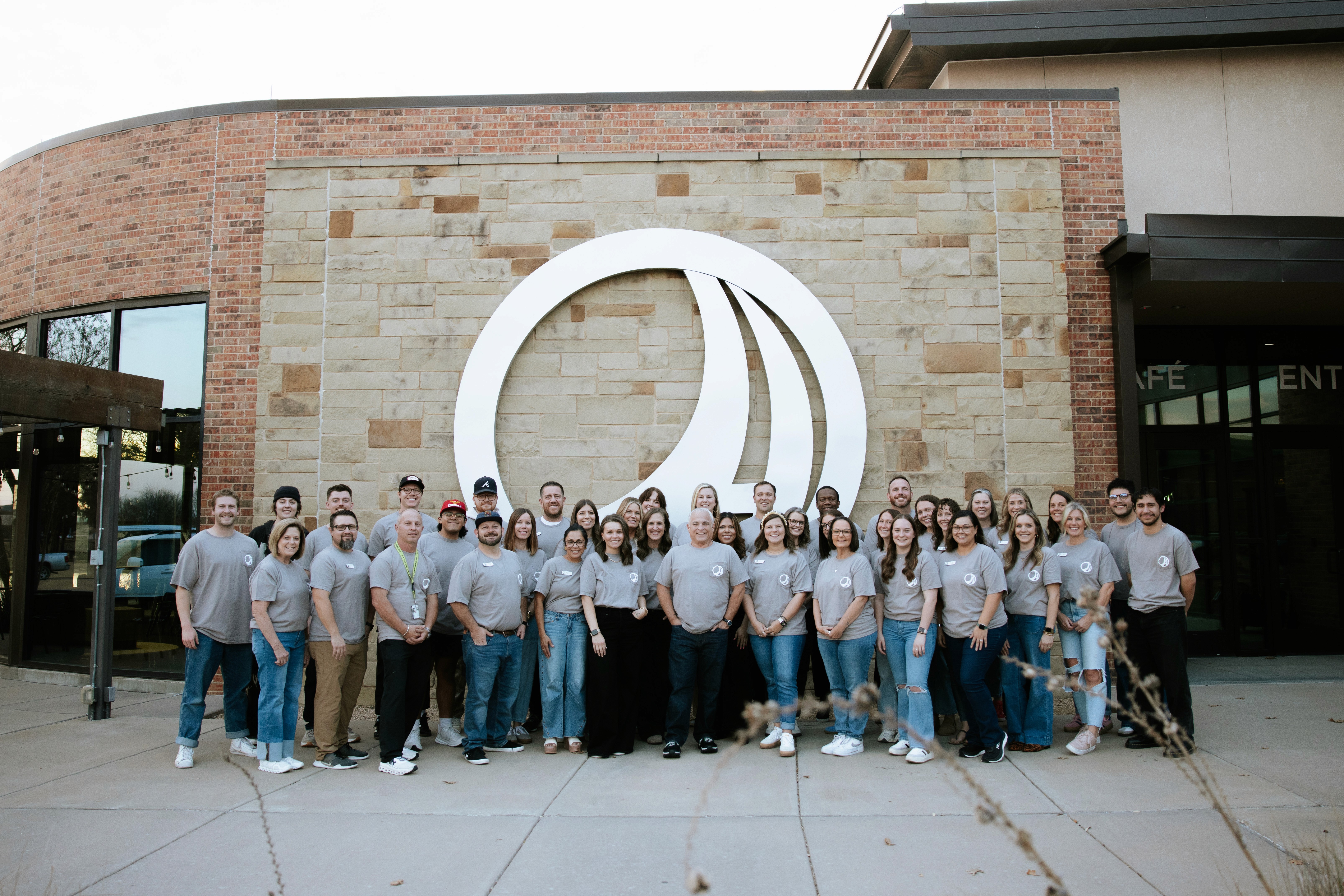 A group of seven people stands together behind a counter in a cafe, smiling and posing for the photo.