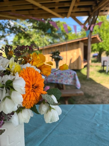 Blomsterbuket fra haven i vase på bordet i havepavillonen hos Egebjerggård Grønt med udsigt til shelteren. 