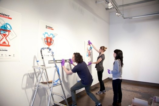 people installing designer as posters on the wall
