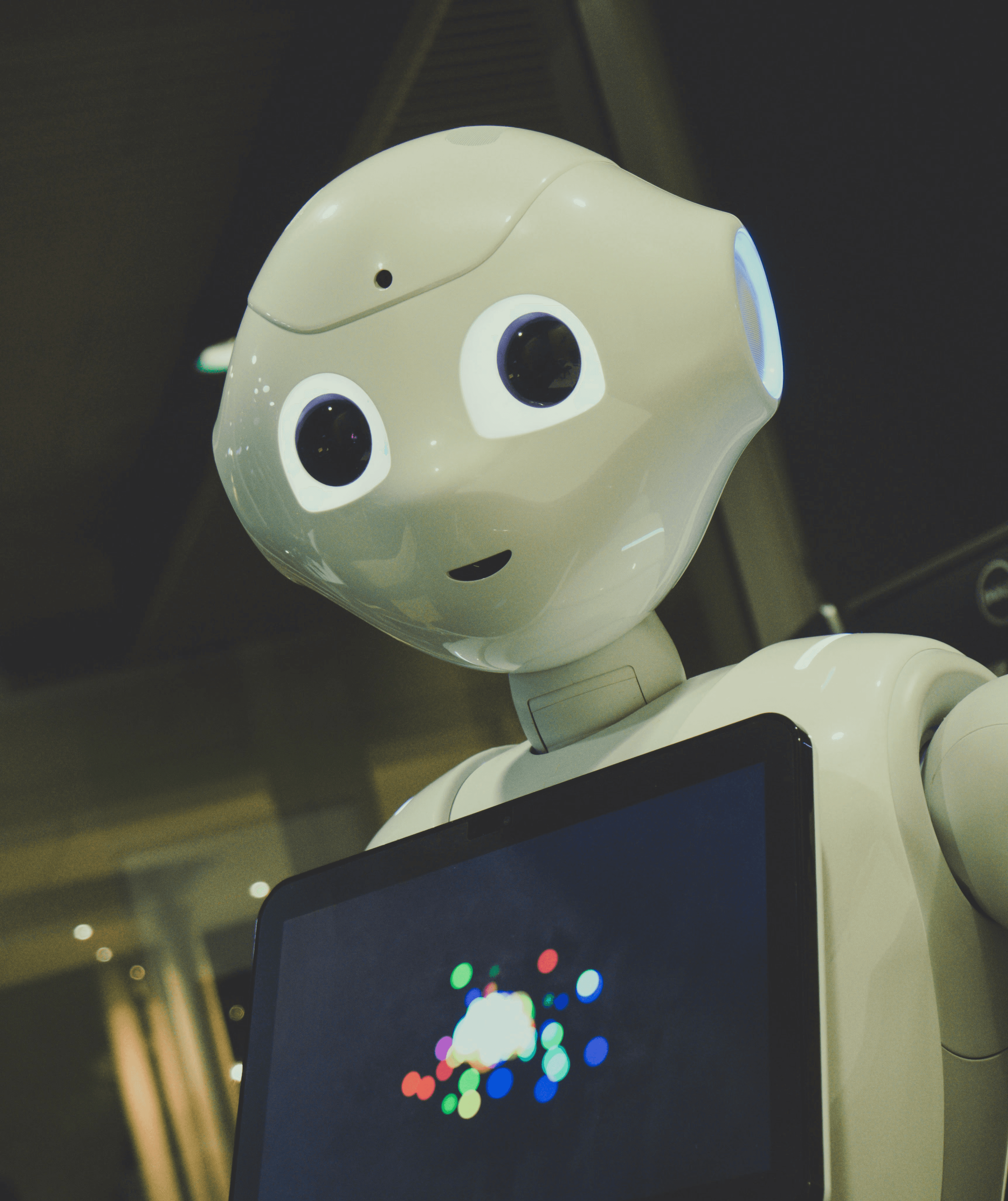 white robot toy holding black tablet