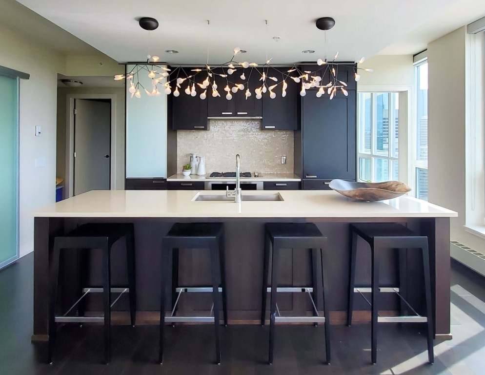 Image of Modern kitchen design with island, sink, and stools, showcasing KHD Homes' interior design and construction expertise.