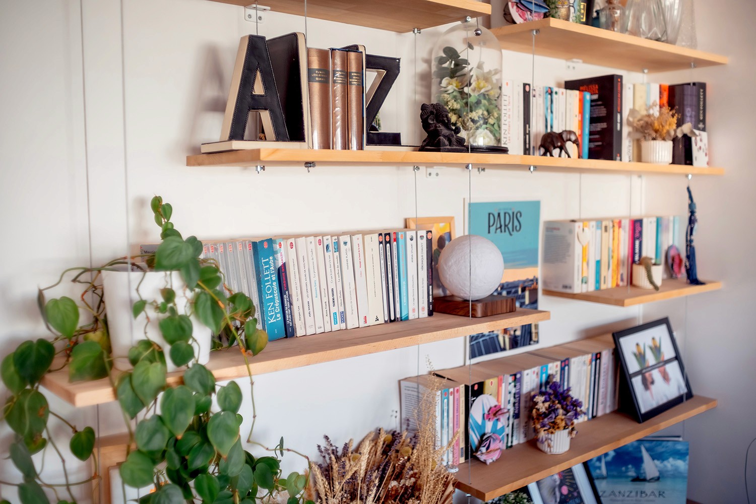 Étagères murales bois avec livres et objets déco dans un intérieur rénové.