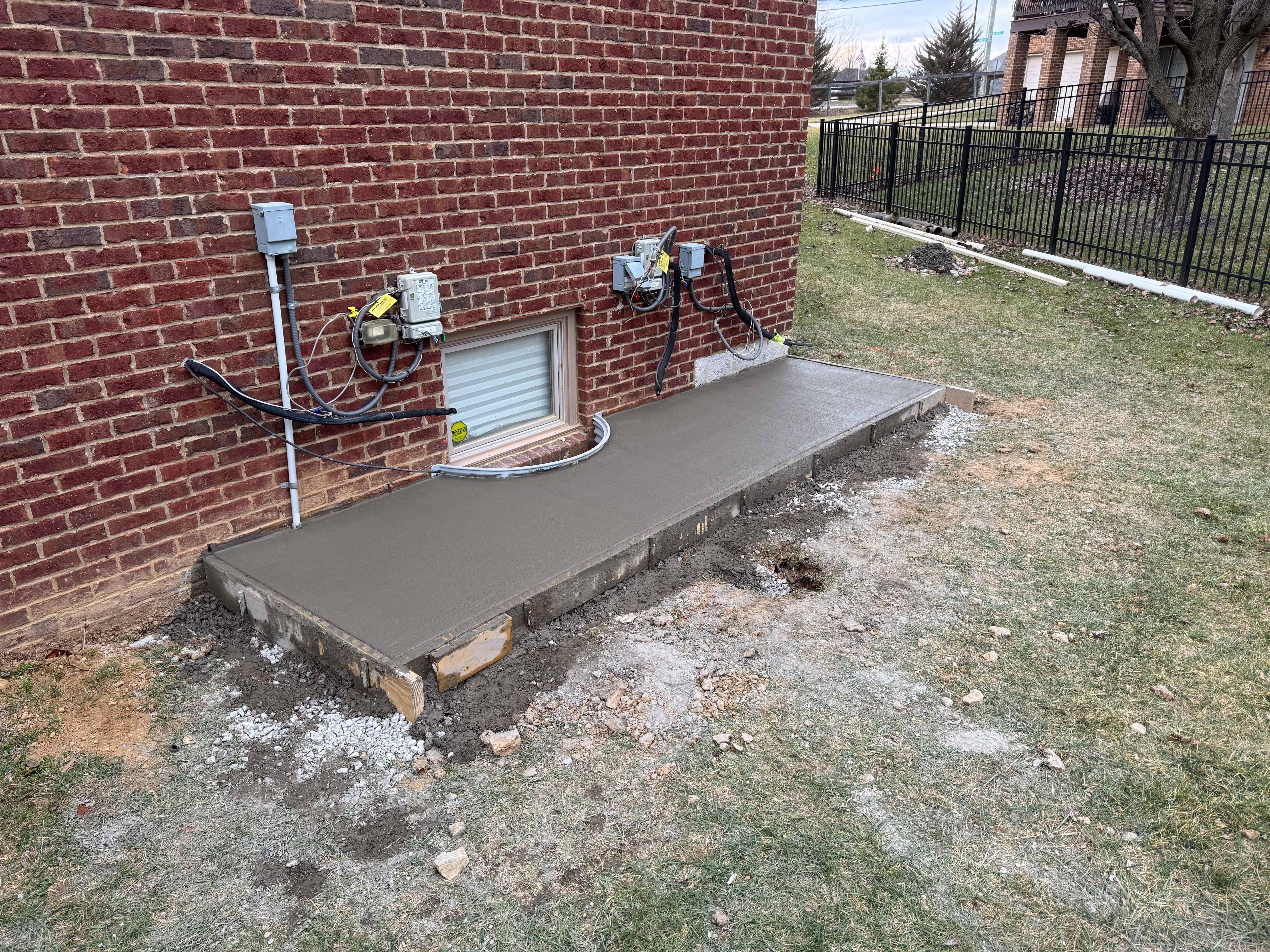 Freshly poured concrete pad under utility meters and window