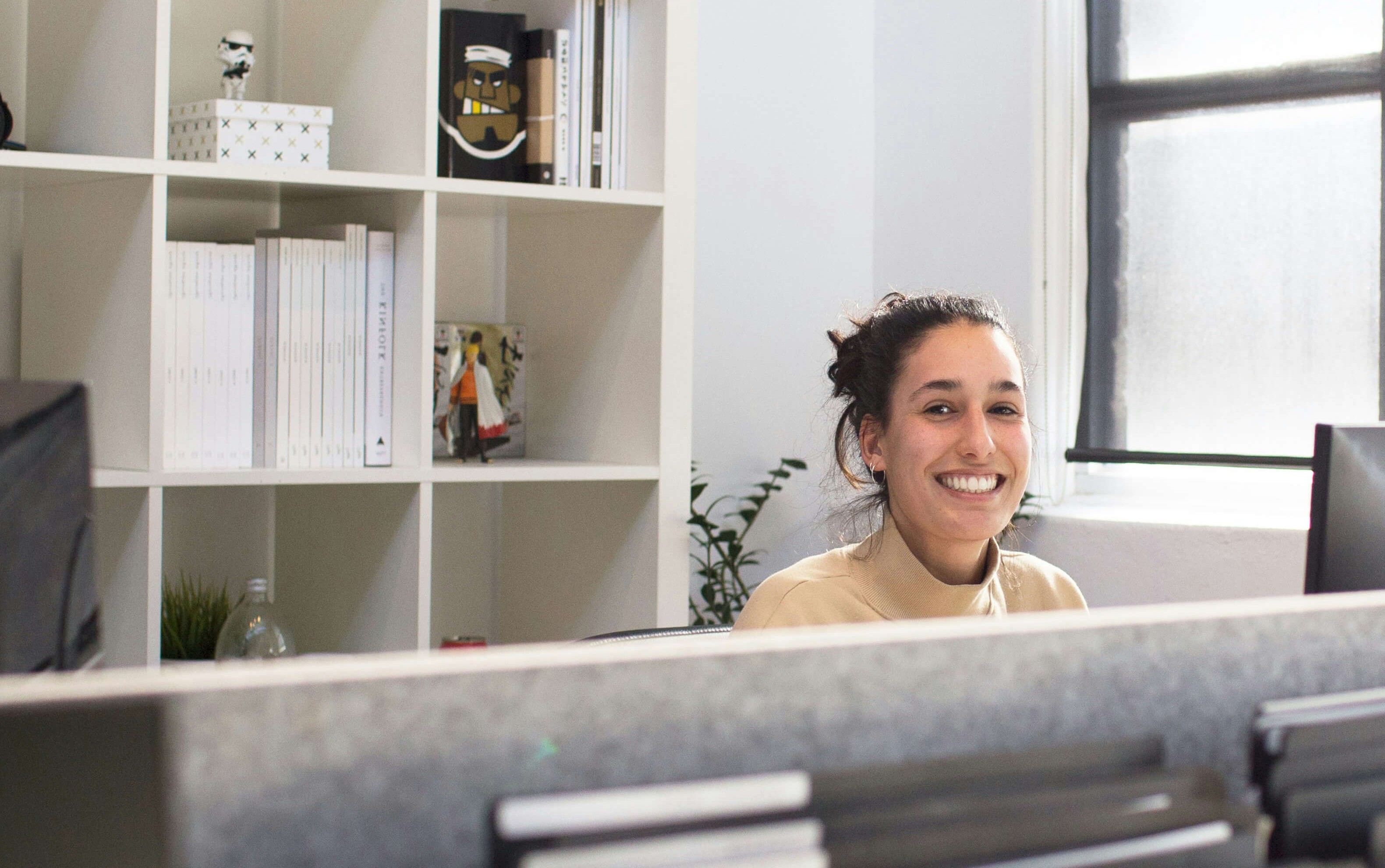 Praxismitarbieterin lächelt freundlich über den Praxistresen hinweg