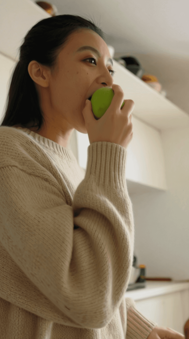 Woman in brown leather jacket posing against a coastal backdrop.