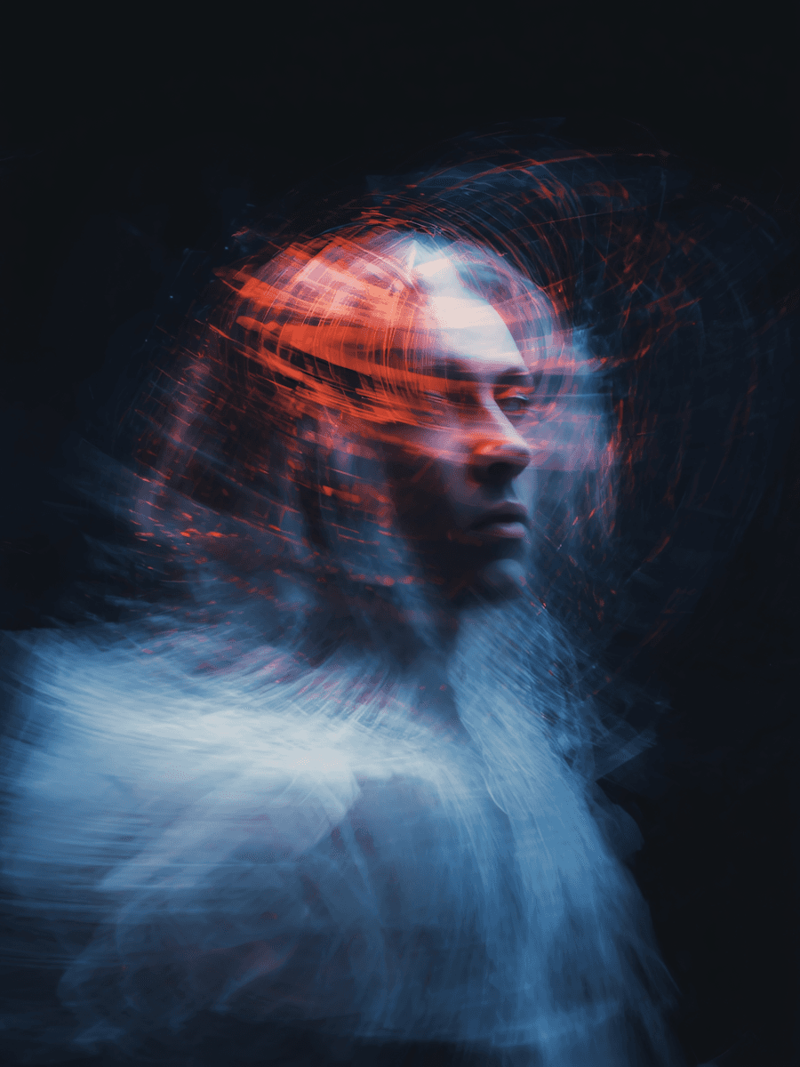 A surreal image of a person surrounded by dynamic light trails, blending warm orange and cool blue tones in a dark, abstract setting.