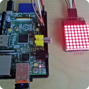 Raspberry Pi single-board computer connected to an 8x8 red LED dot matrix display and laser transmitter module via GPIO pins for an IoT electronics project.