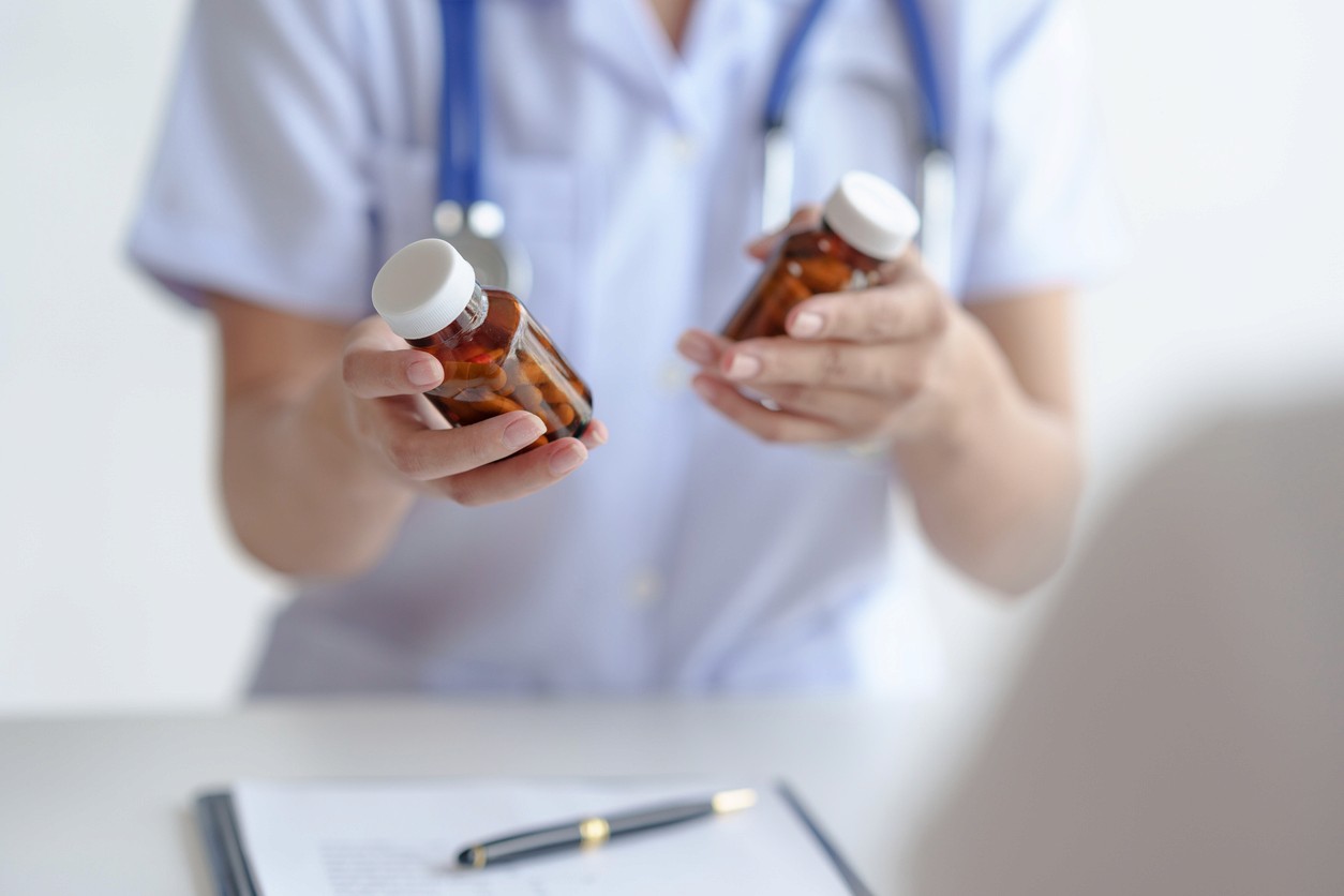 A healthcare professional in blue scrubs carefully handling medication tablets