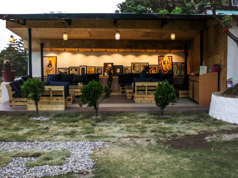 Rustic gallery: A casual outdoor living space defined by raw wooden textures, dark upholstery, and a vibrant backdrop of framed art.