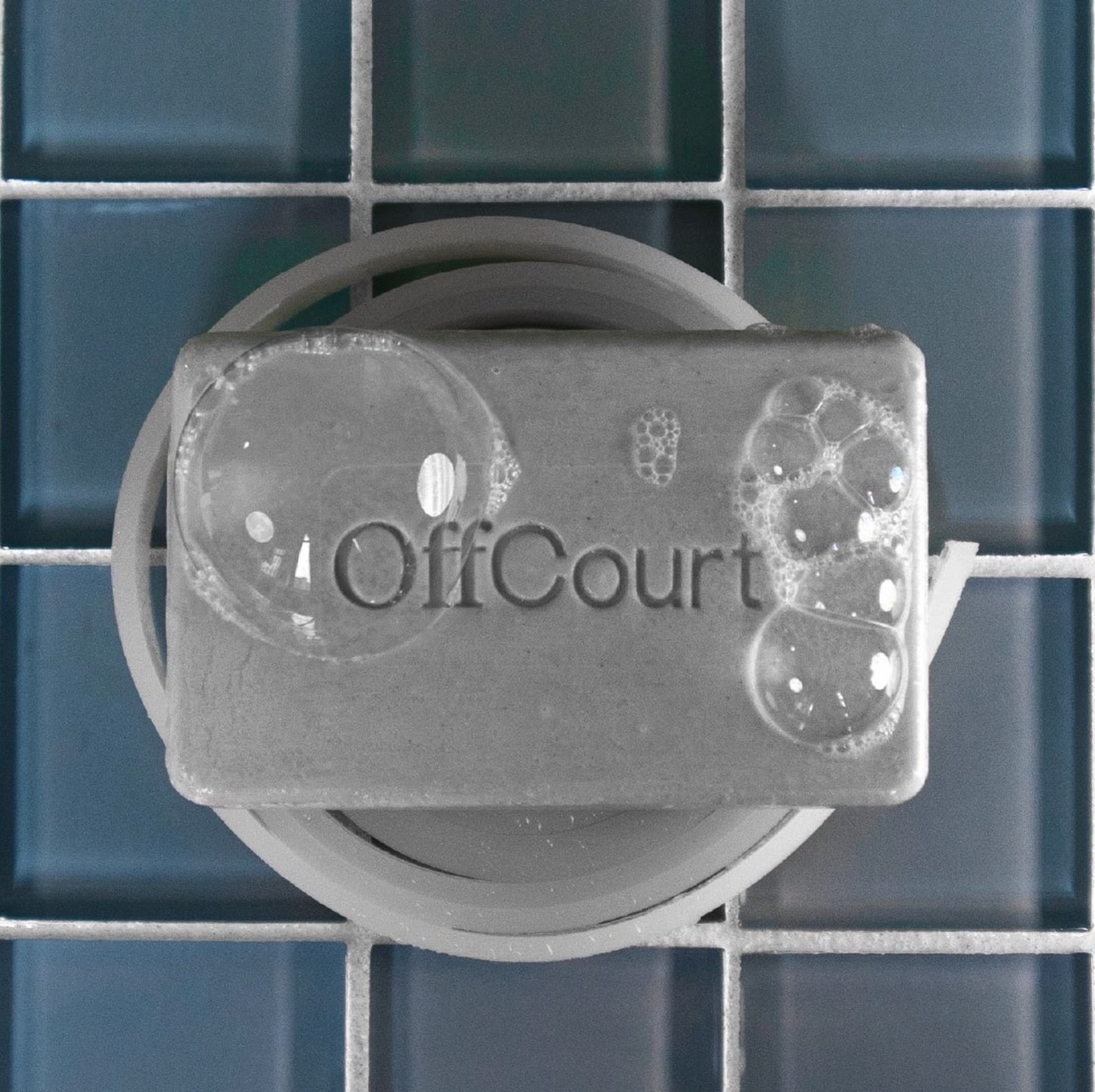 A clear soap bar on a circular dish, resting on a blue tiled surface.