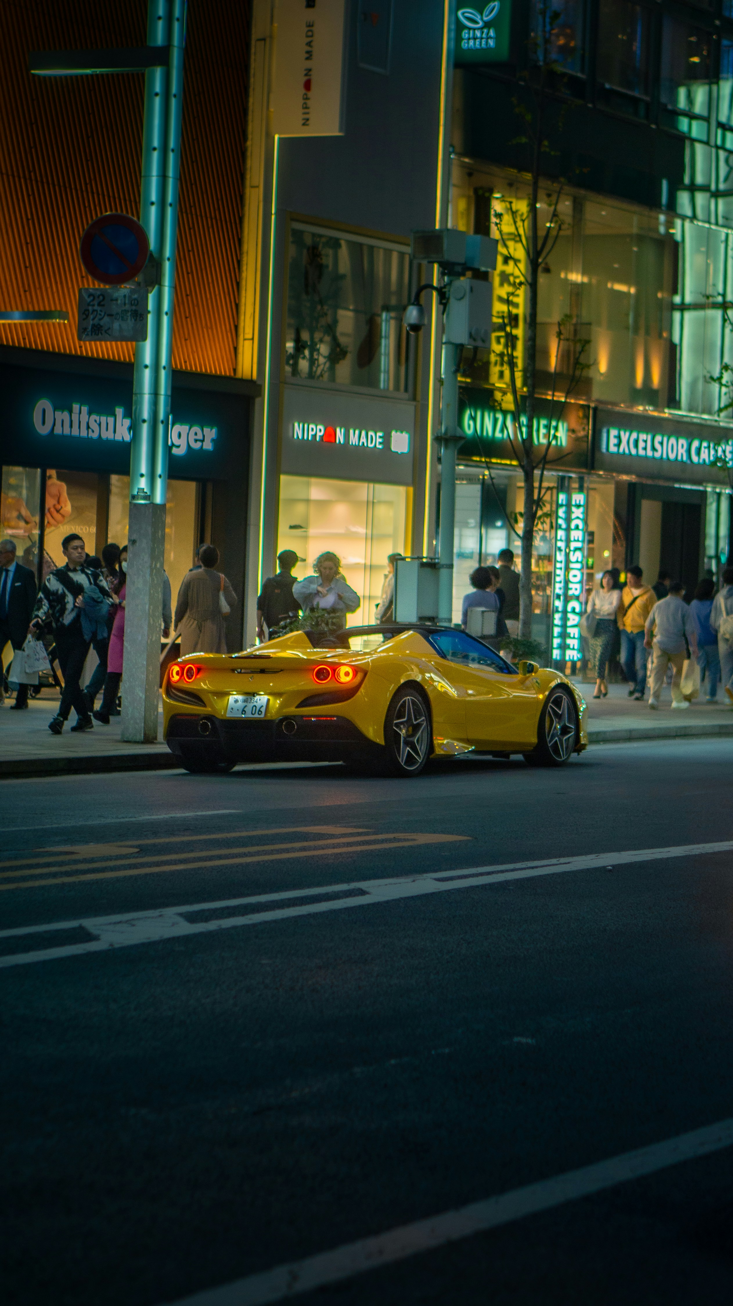 a yellow sports car driving down a street at night