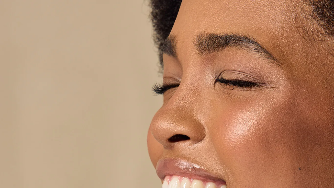 A woman laughs with her eyes closed as she lifts a Sēkret capsule to her lips