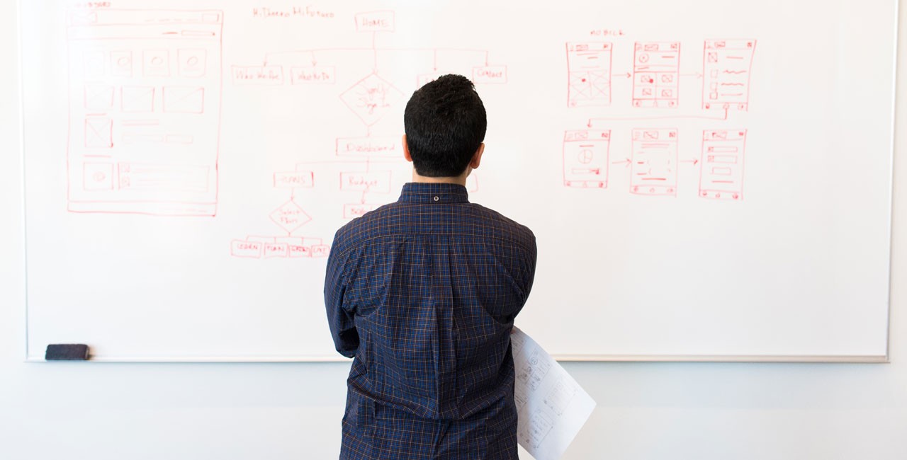 Participant adding notes to a board covered in sticky notes during an affinity diagramming exercise