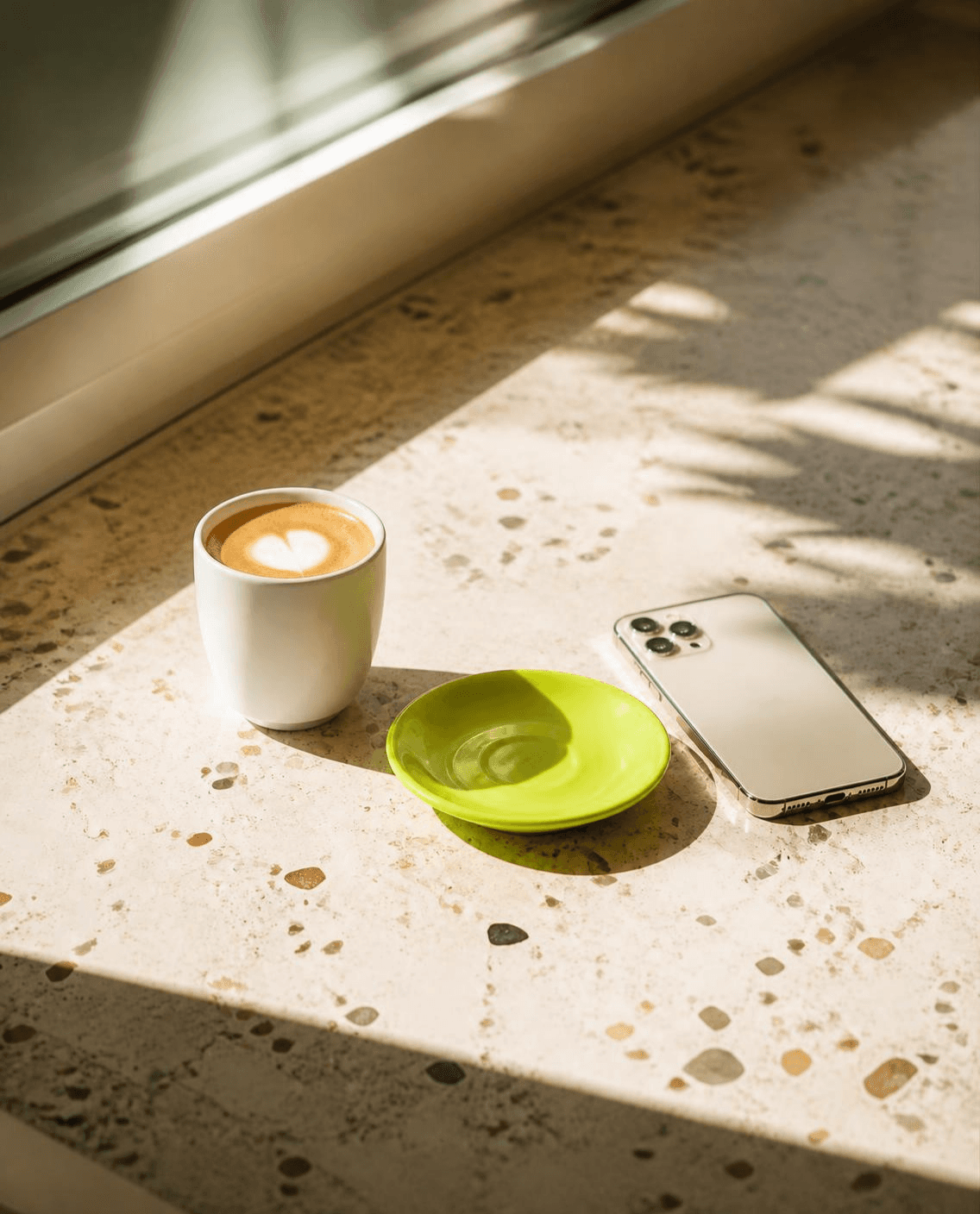Cortado on terrazzo with a lime saucer and phone