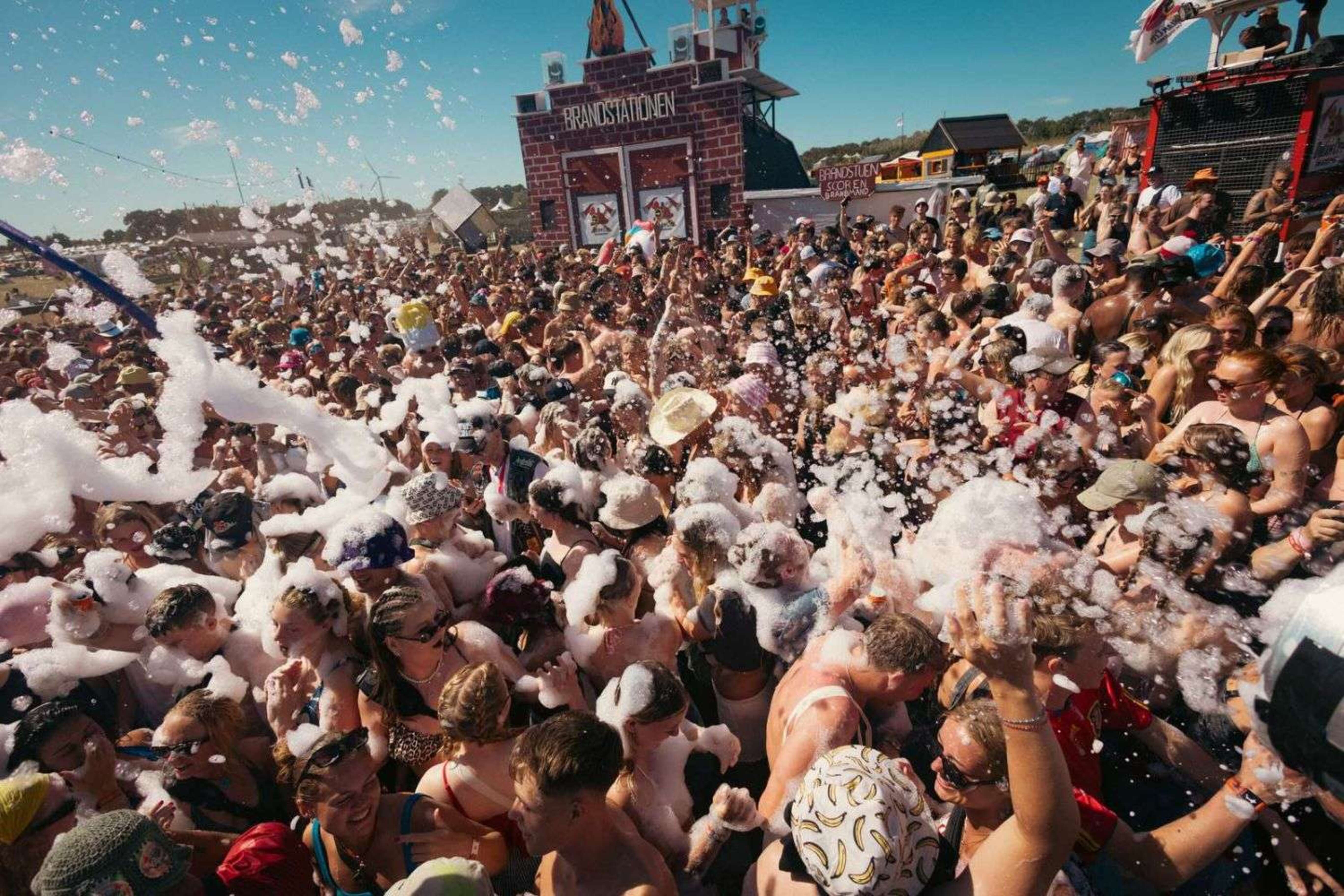 Festival crowd celebrating in a foam-filled party area at Roskilde Festival.