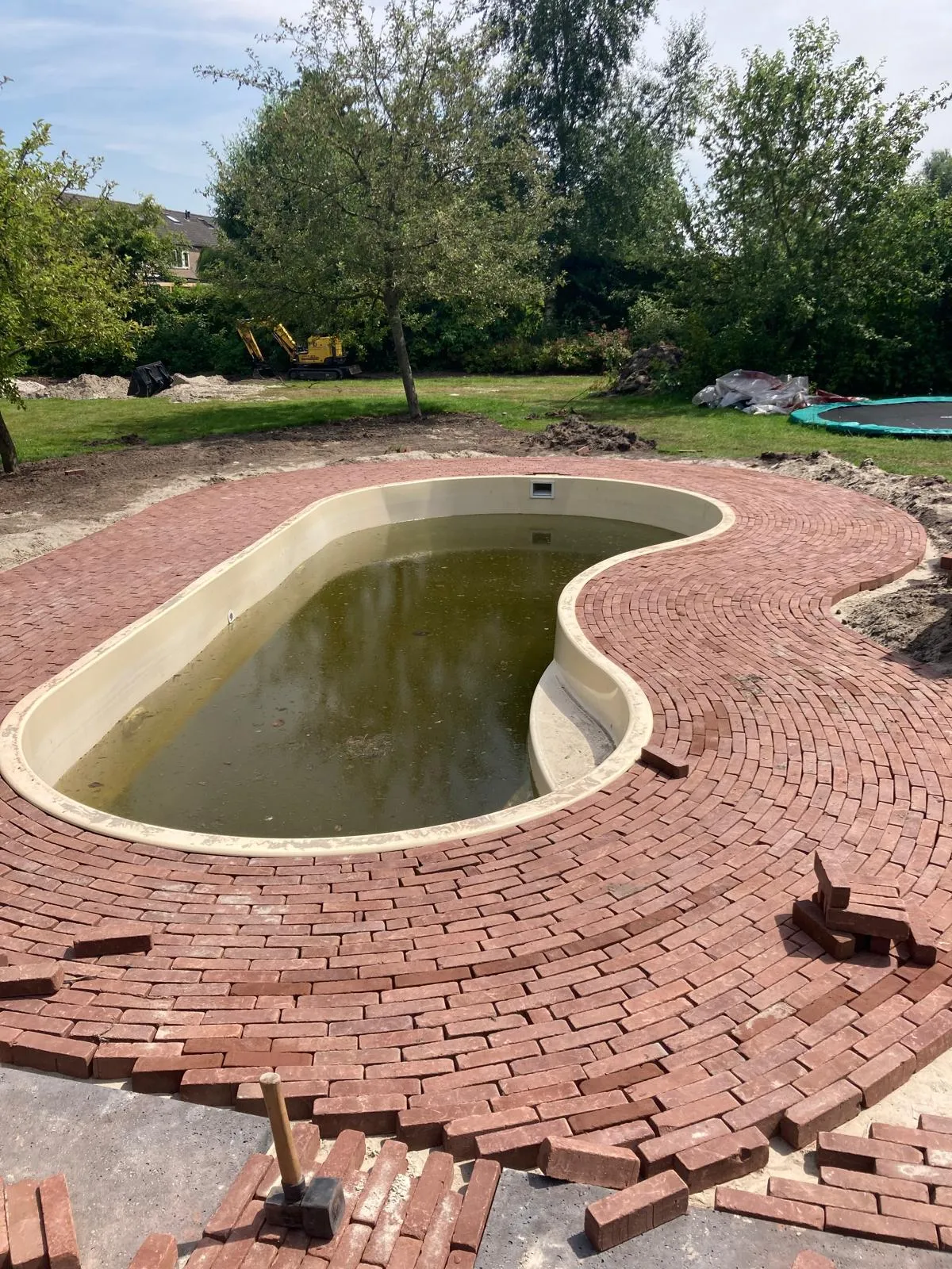 Gebakken klinkerbestrating rond organisch gevormde vijver als tuinpad en terras in Friesland