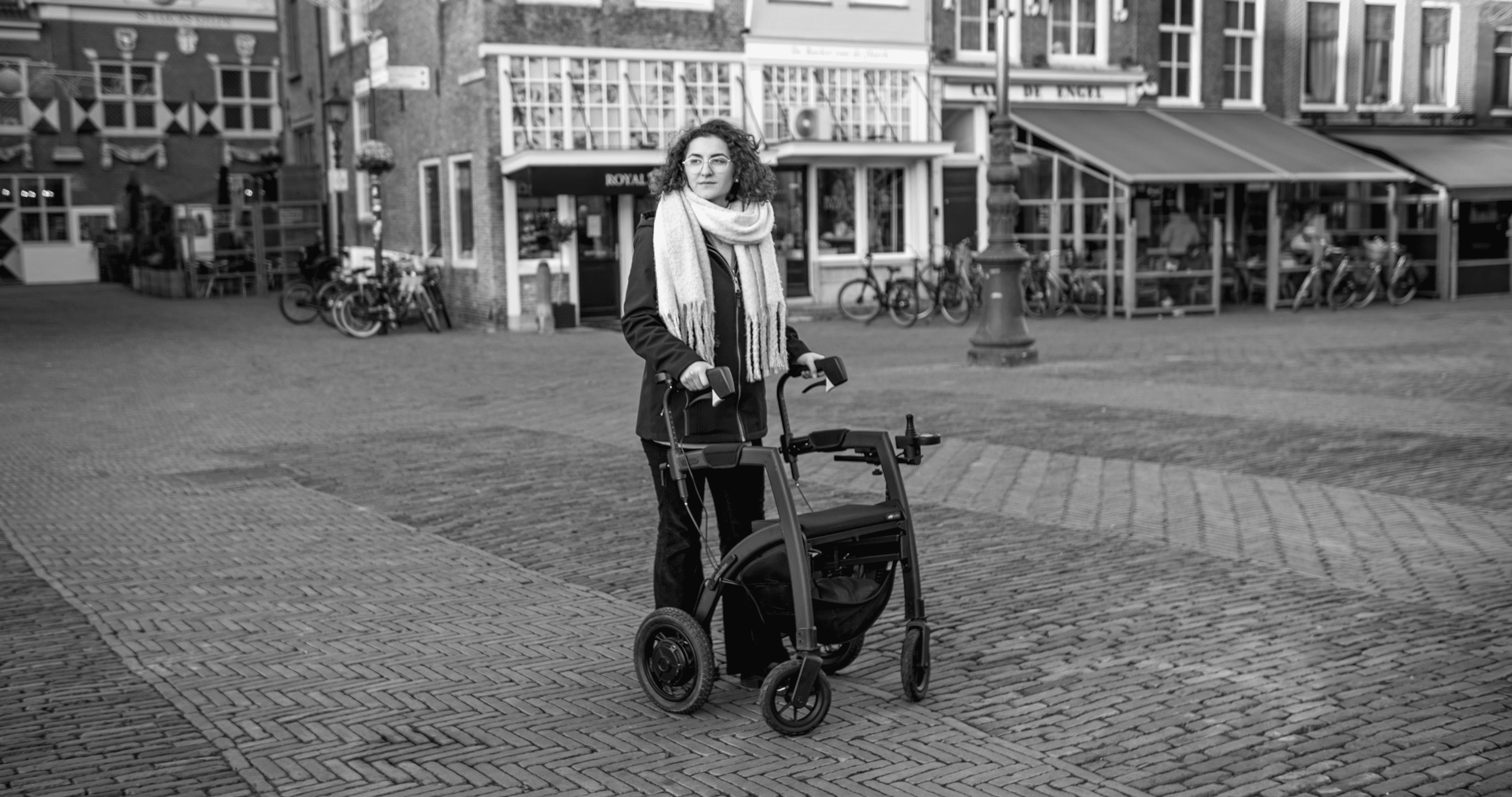a woman with a walker on a cobblestone street