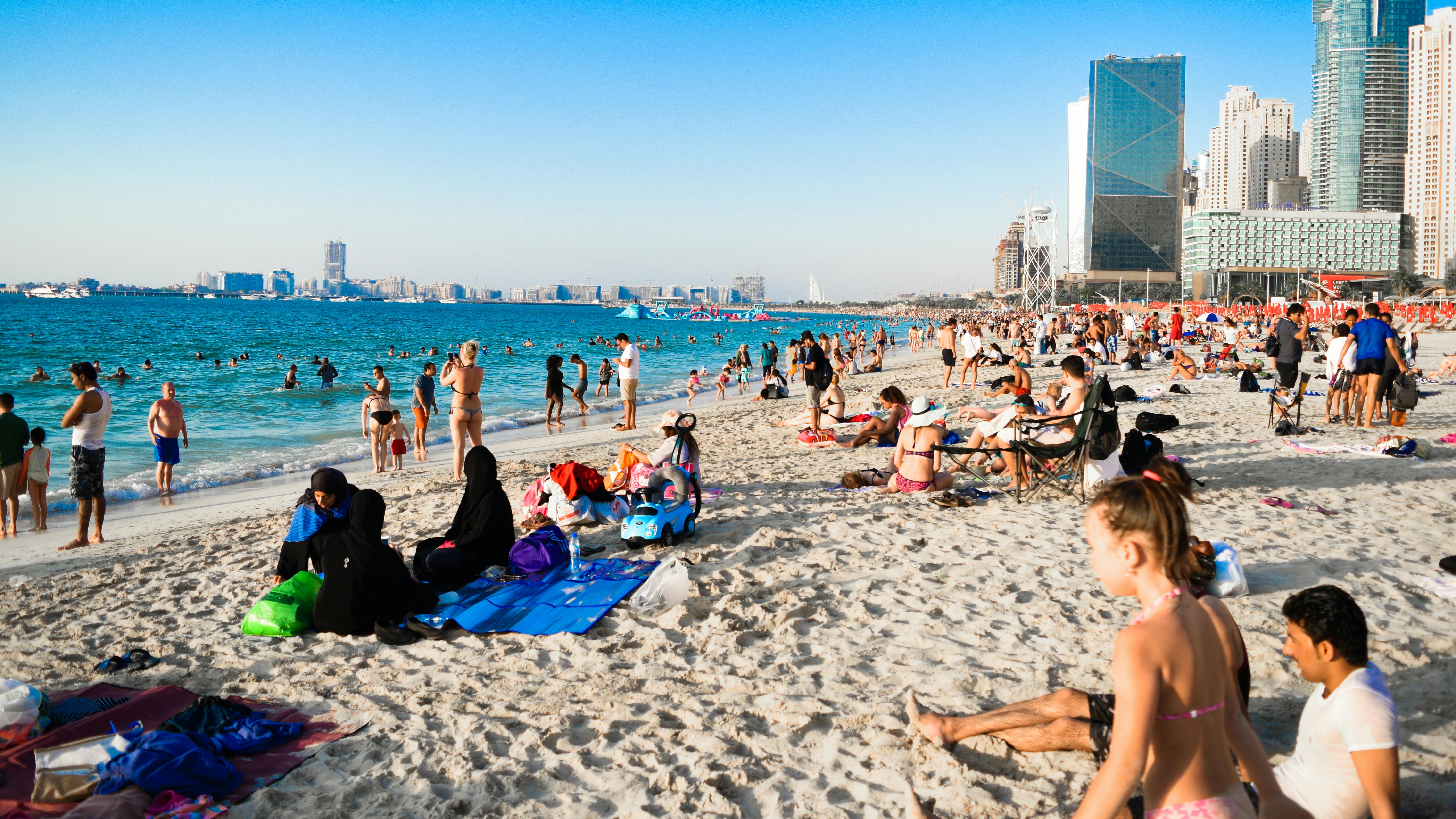 Tourists and locals relax and swim on one of Dubai's beaches during summer.