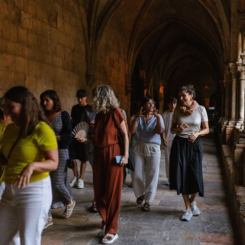 En grupp människor som går genom en svagt upplyst, välvd sten korridor.