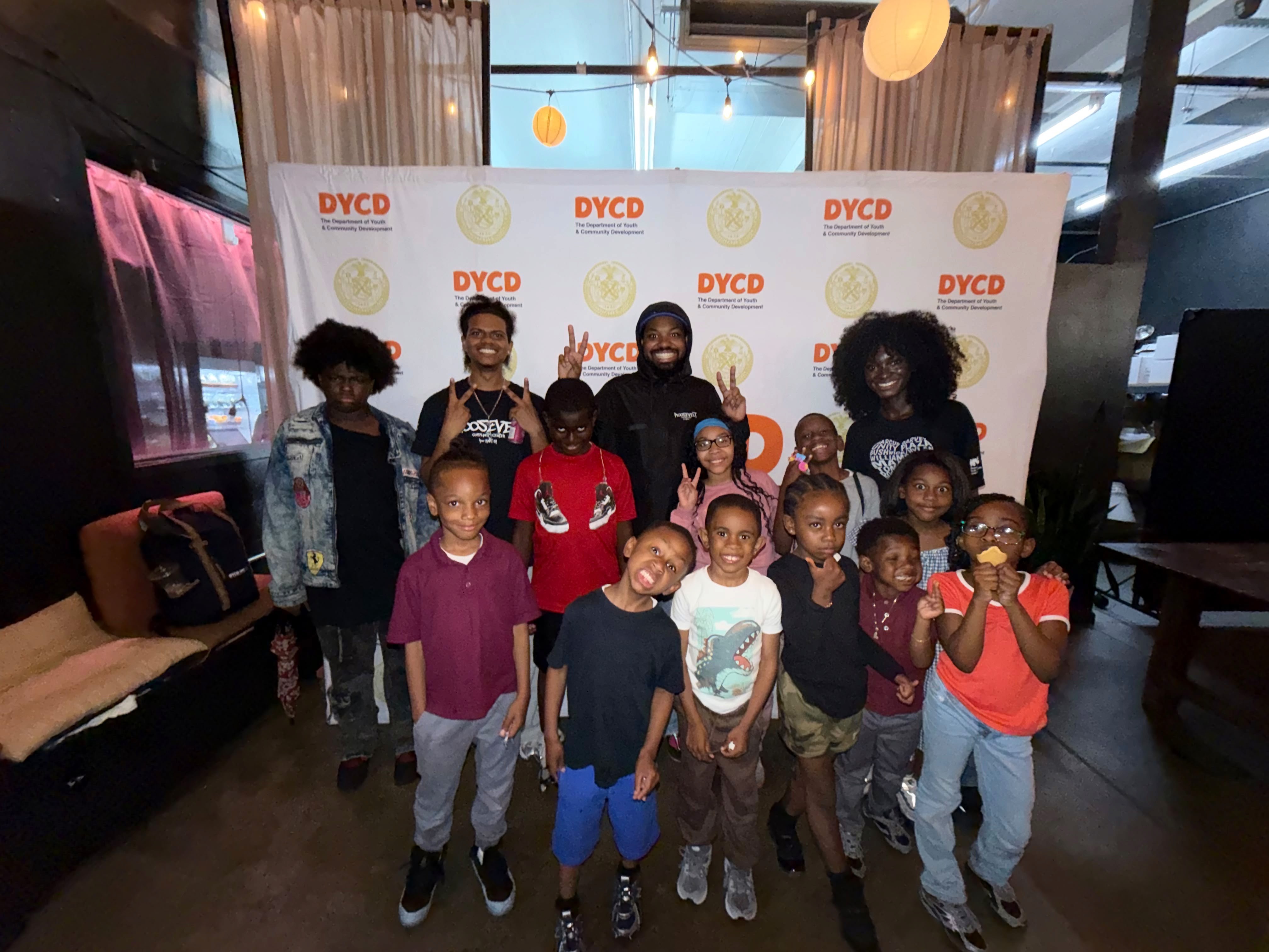 Youth pose in front of a DYCD step-and-repeat.