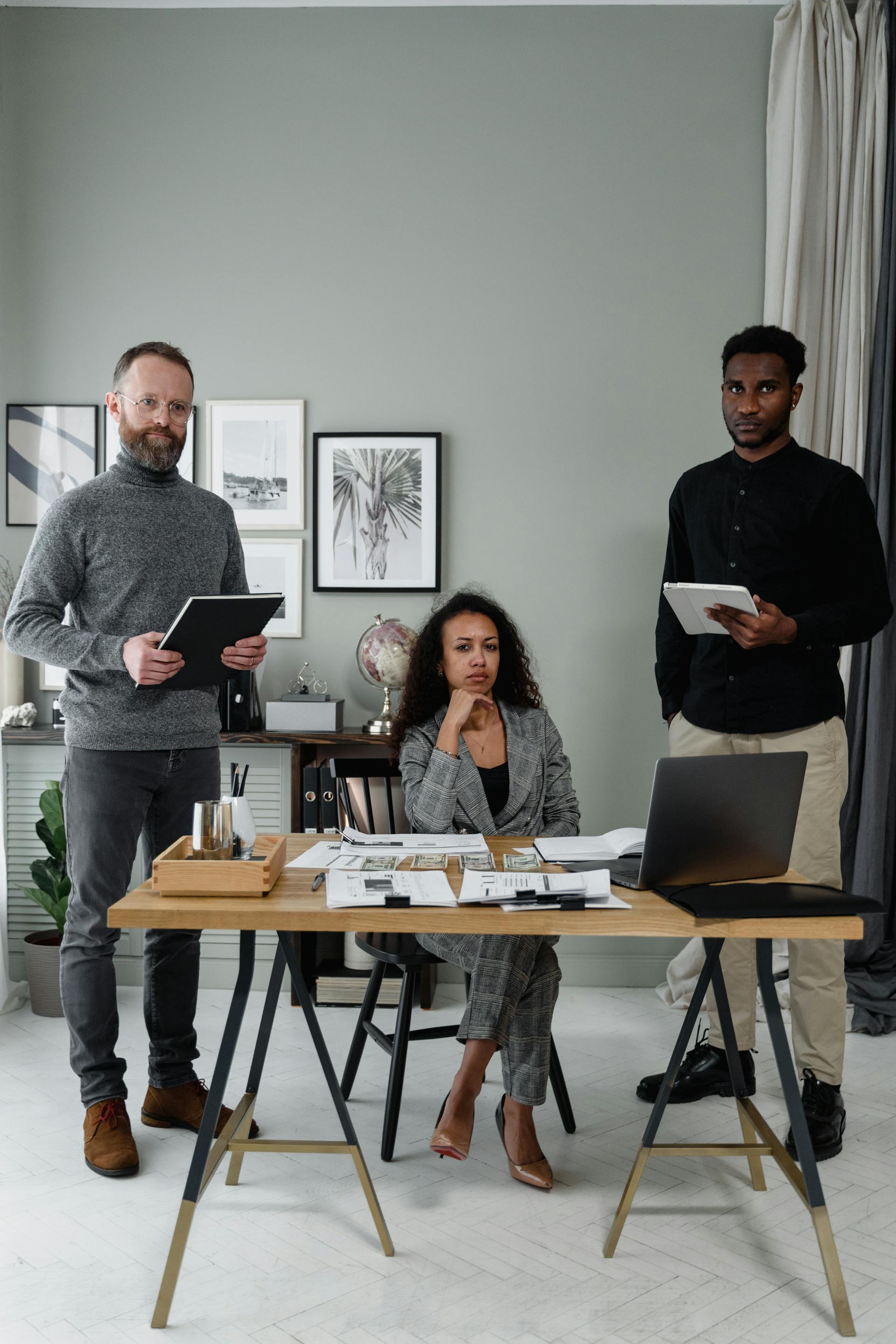 A team of 3 in an office looking towards the camera