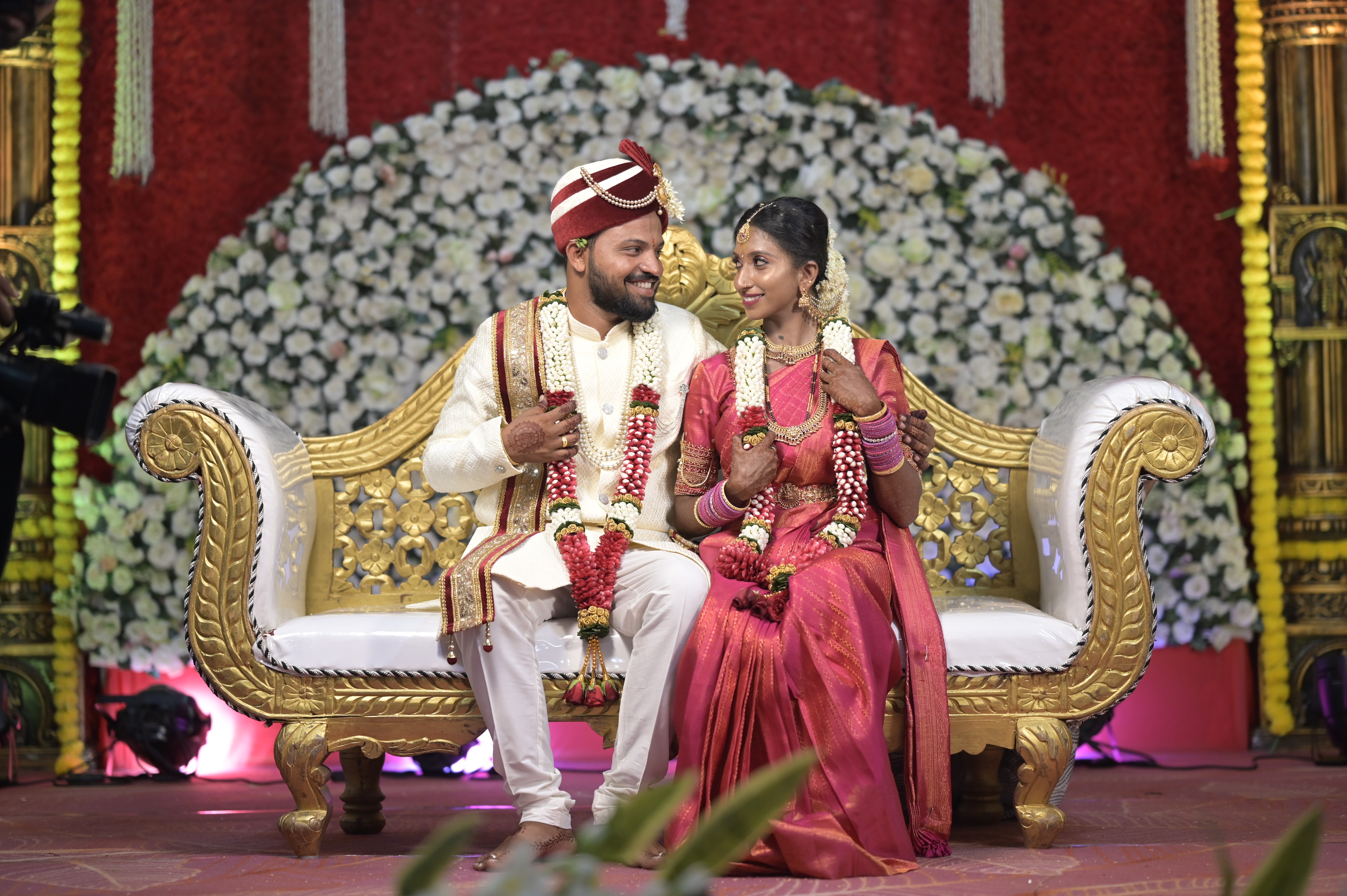 Bride and groom in traditional Indian wedding attire seated together on a decorated stage