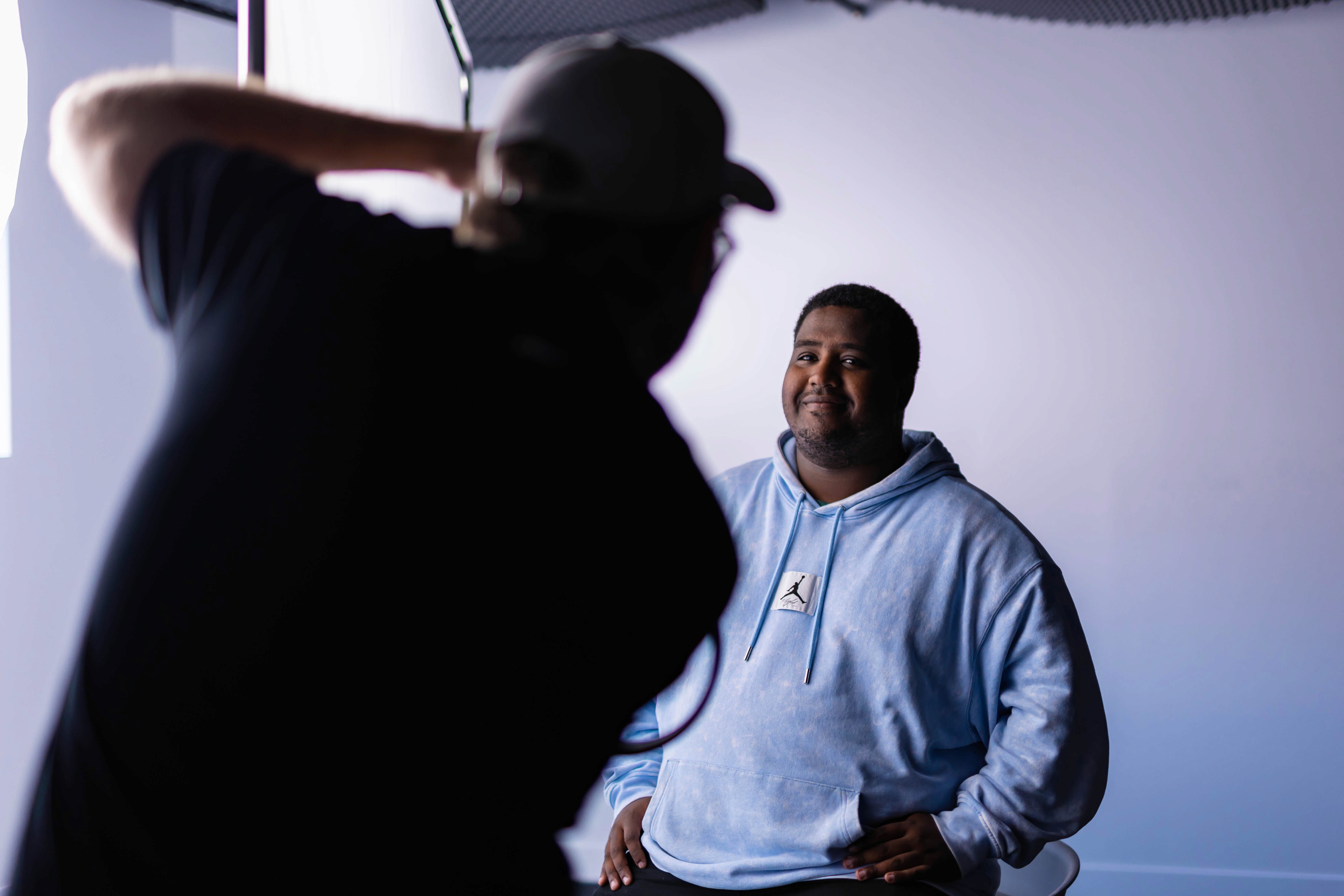 Two filmmakers operate a large camera in a dimly lit studio, wearing headphones and focused intently on the screen, conveying concentration.