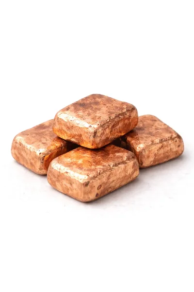 Four neatly stacked, shiny brown copper ingots arranged on a clean, white background.