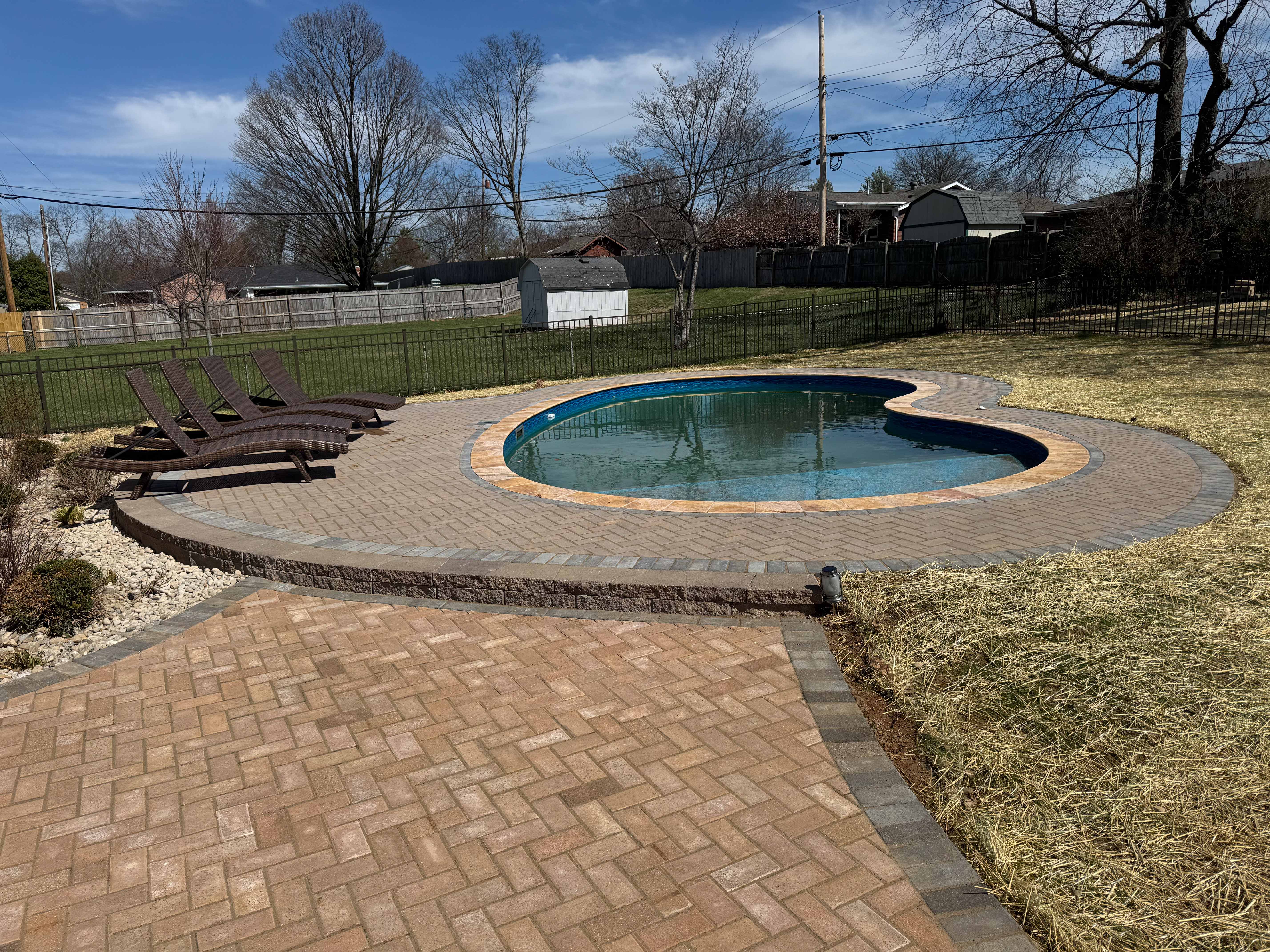 Brick paver pool deck with integrated retaining wall edge