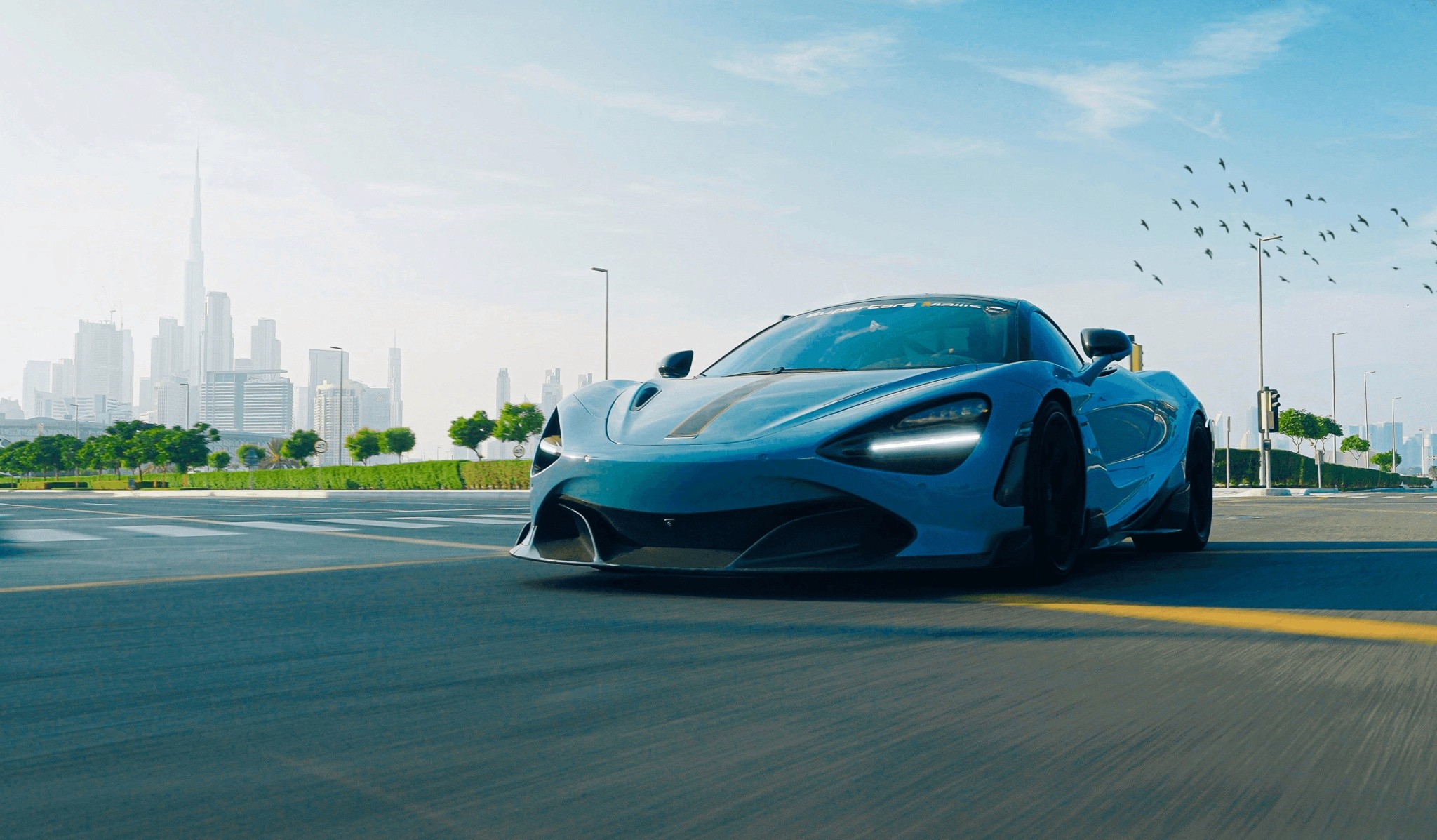 A sleek, high-performance sports car speeds down an urban highway with a modern city skyline in the background, set under a clear blue sky, emphasizing luxury and speed.