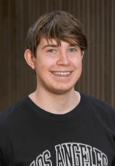 Portrait of a laughing person with curly hair wearing a white shirt