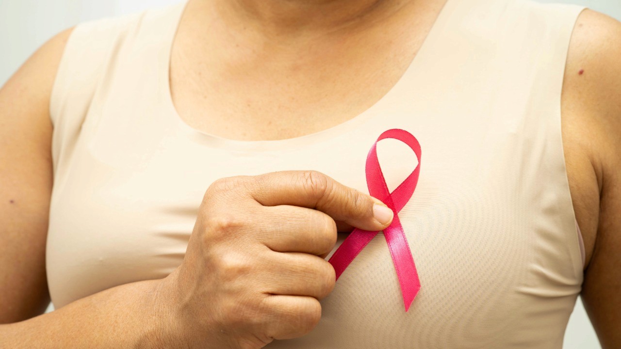 woman holding cancer ribbon infront of chest