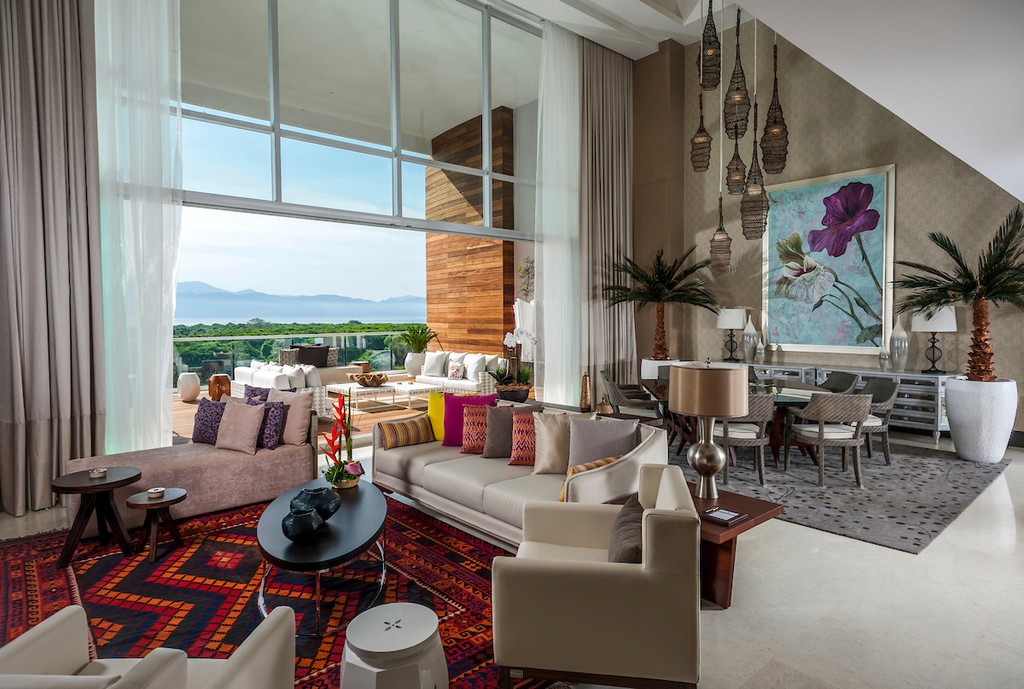 Couple standing on a balcony with binoculars in hand looking out over the ocean