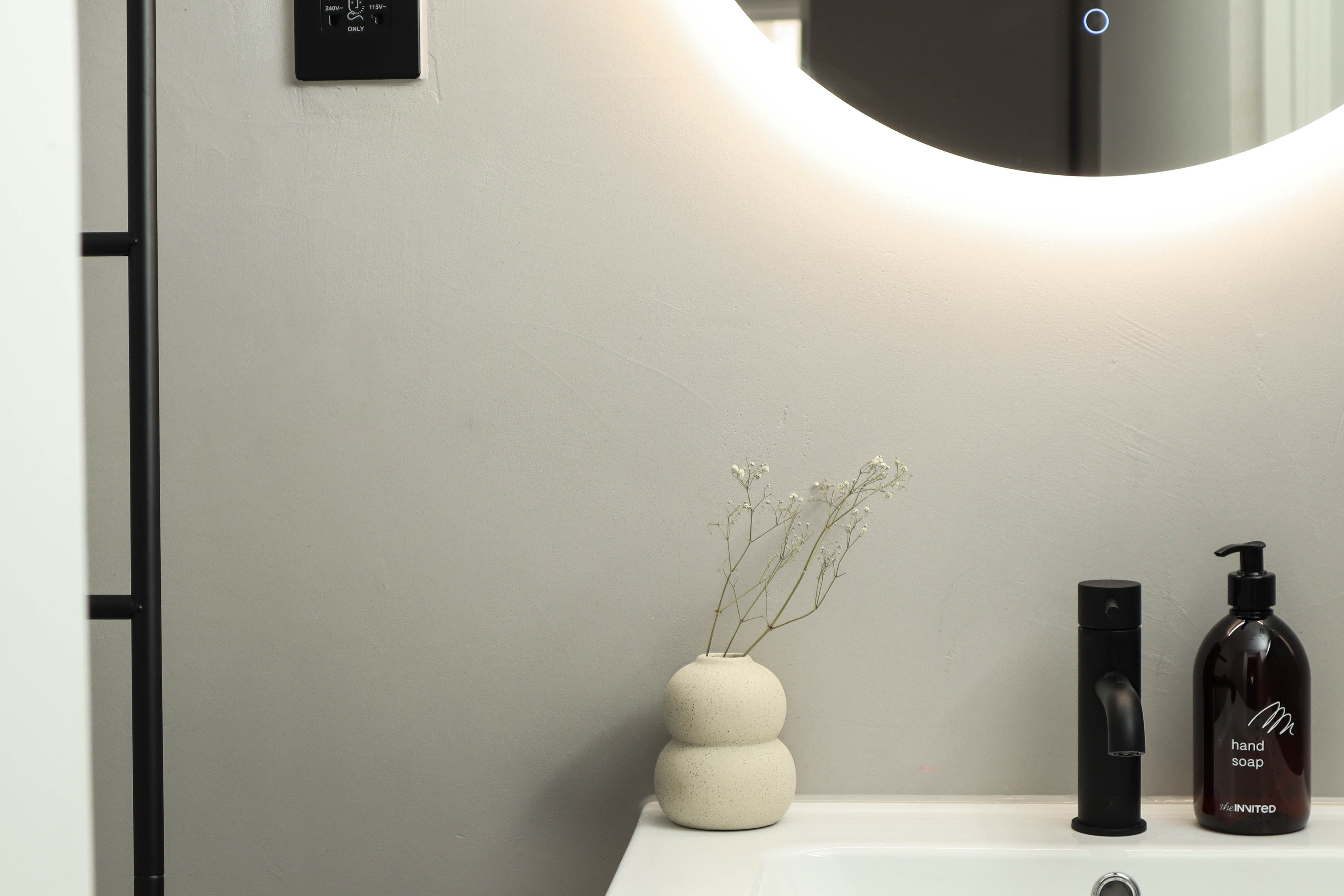 Bright modern bathroom with minimalist vase and backlit mirror