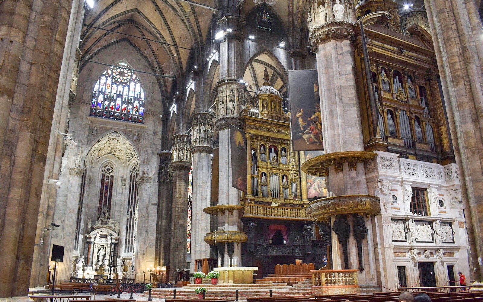 Vista interior del Duomo de la Catedral de Milán con columnas ornamentadas y vitrales coloridos.