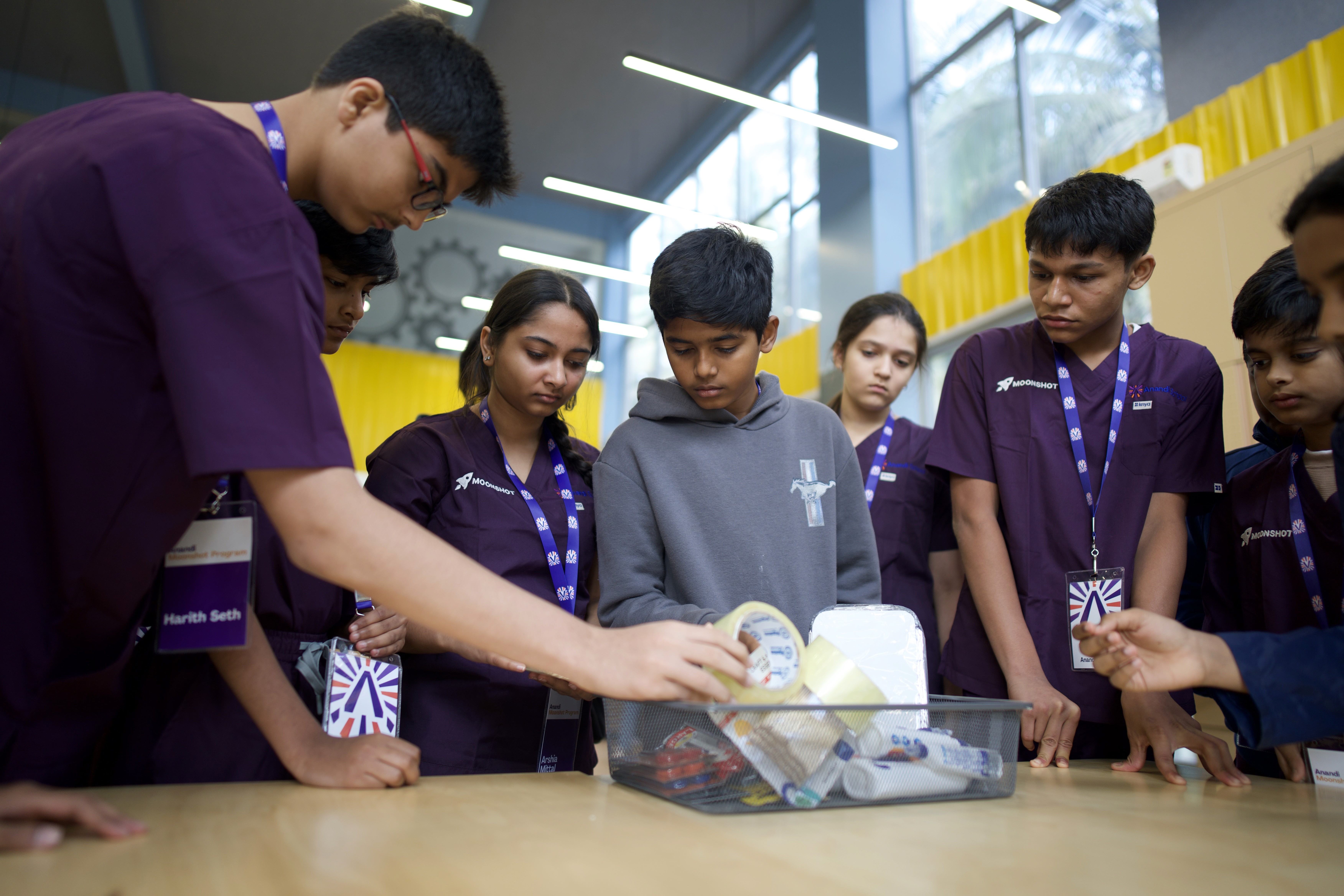 Students observe peer taping recyclables into a sculpture, sparking creativity.