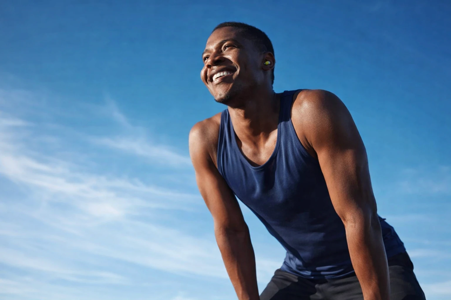Smiling man in athletic wear outdoors, enjoying a moment after physical activity