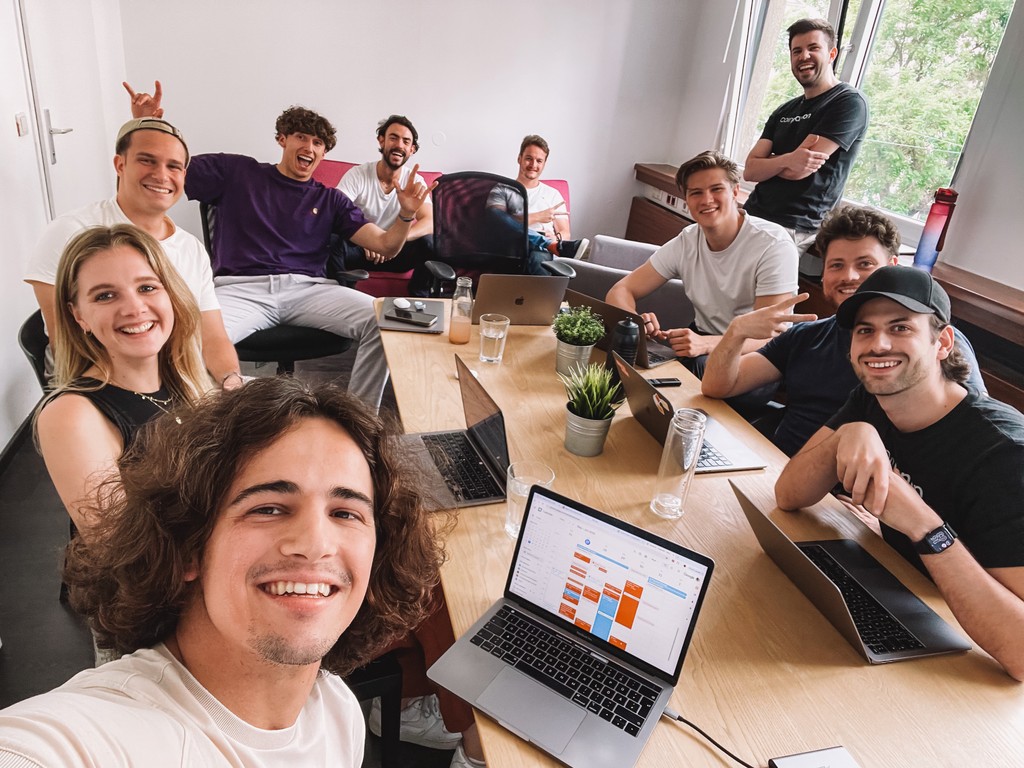 Gruppe von jungen Teammitgliedern bei einem Meeting, fröhliche Atmosphäre mit Laptops auf einem Konferenztisch